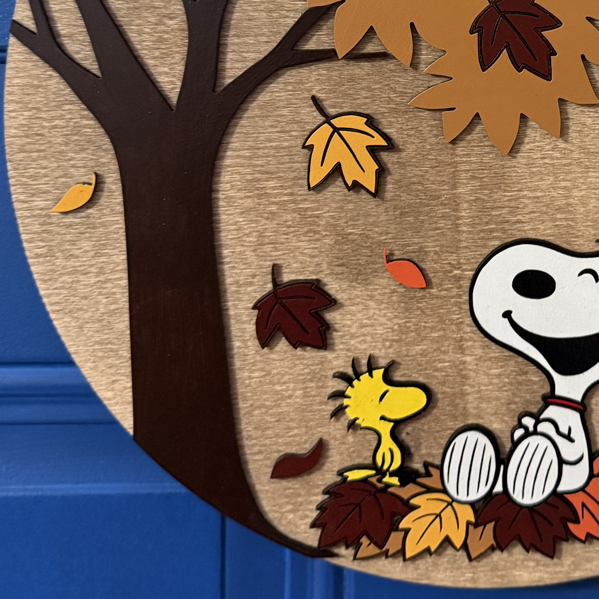 Close-up of fall door hanger highlighting painted leaves, bow details, and character accents