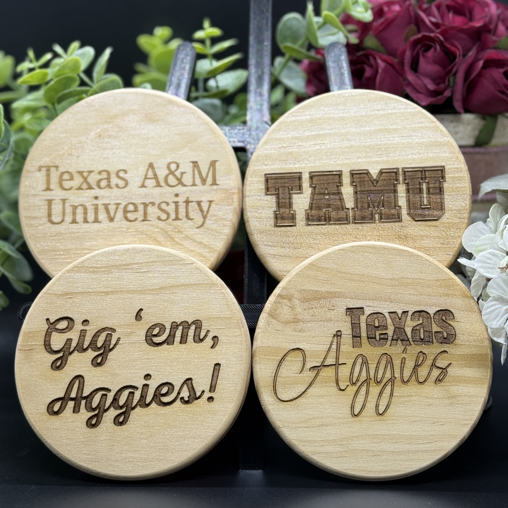 Set of four round Texas A&M engraved wooden coasters with designs including Texas A&M University, TAMU lettermark, Gig ’em Aggies, and Texas Aggies