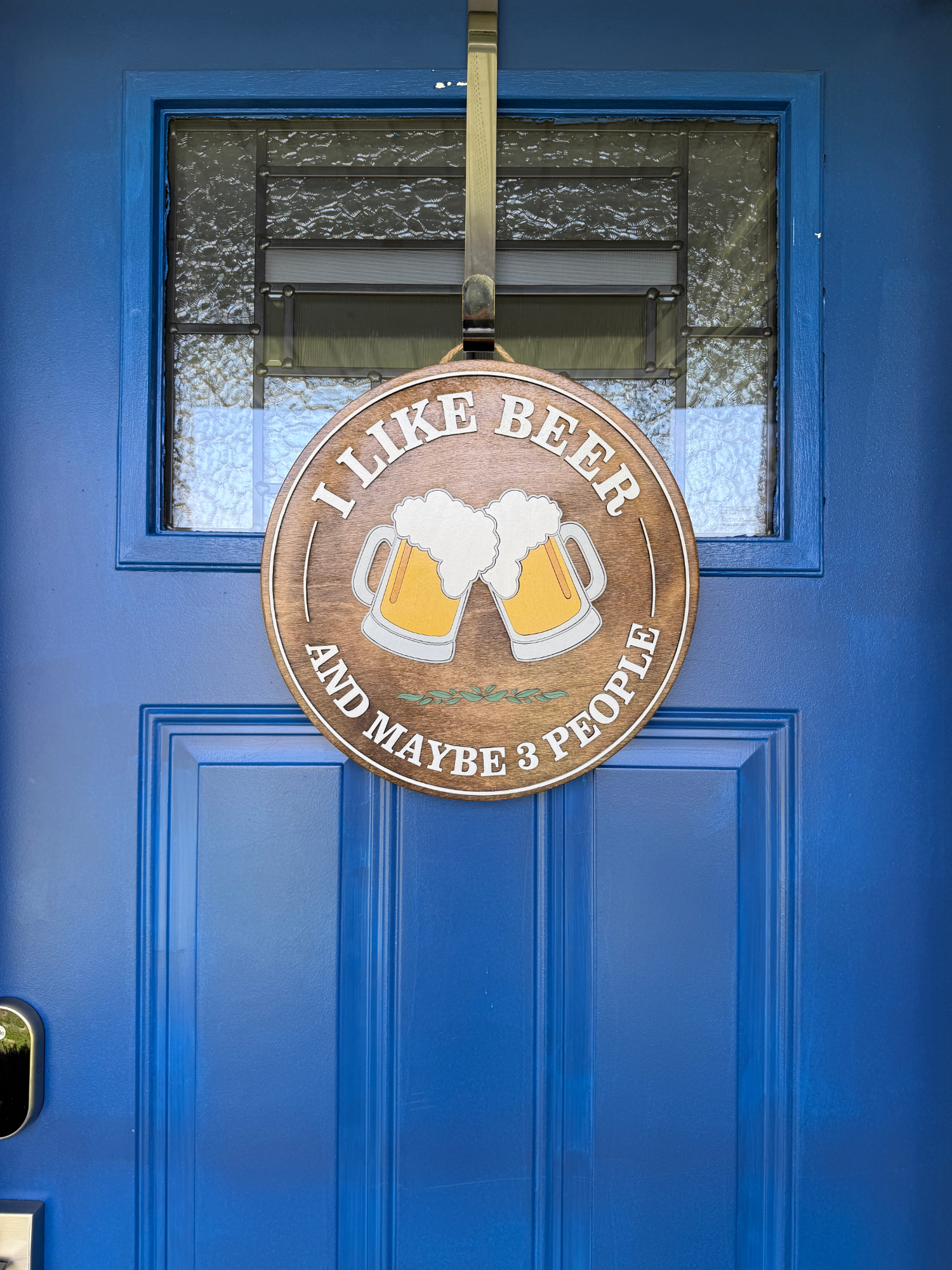 Full door view of rustic beer-themed wood sign hanging on a bright blue front door