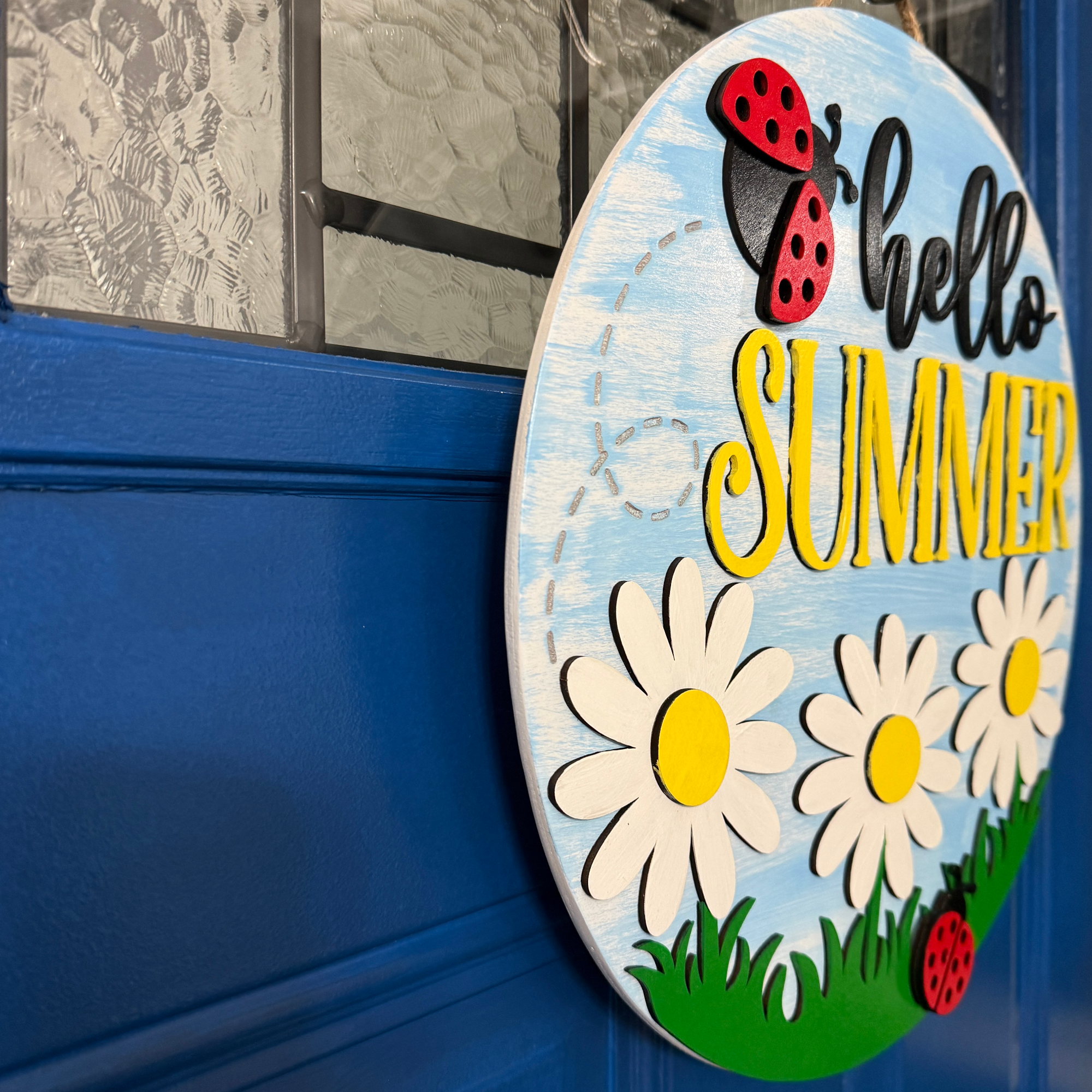 Angled side view of summer door hanger showing layered wood design and depth of daisies and lettering