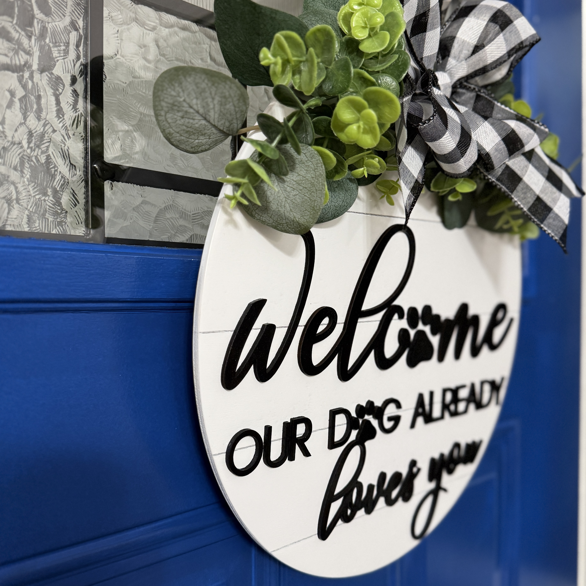 Angled view of welcome sign with paw print lettering and black script text on white background