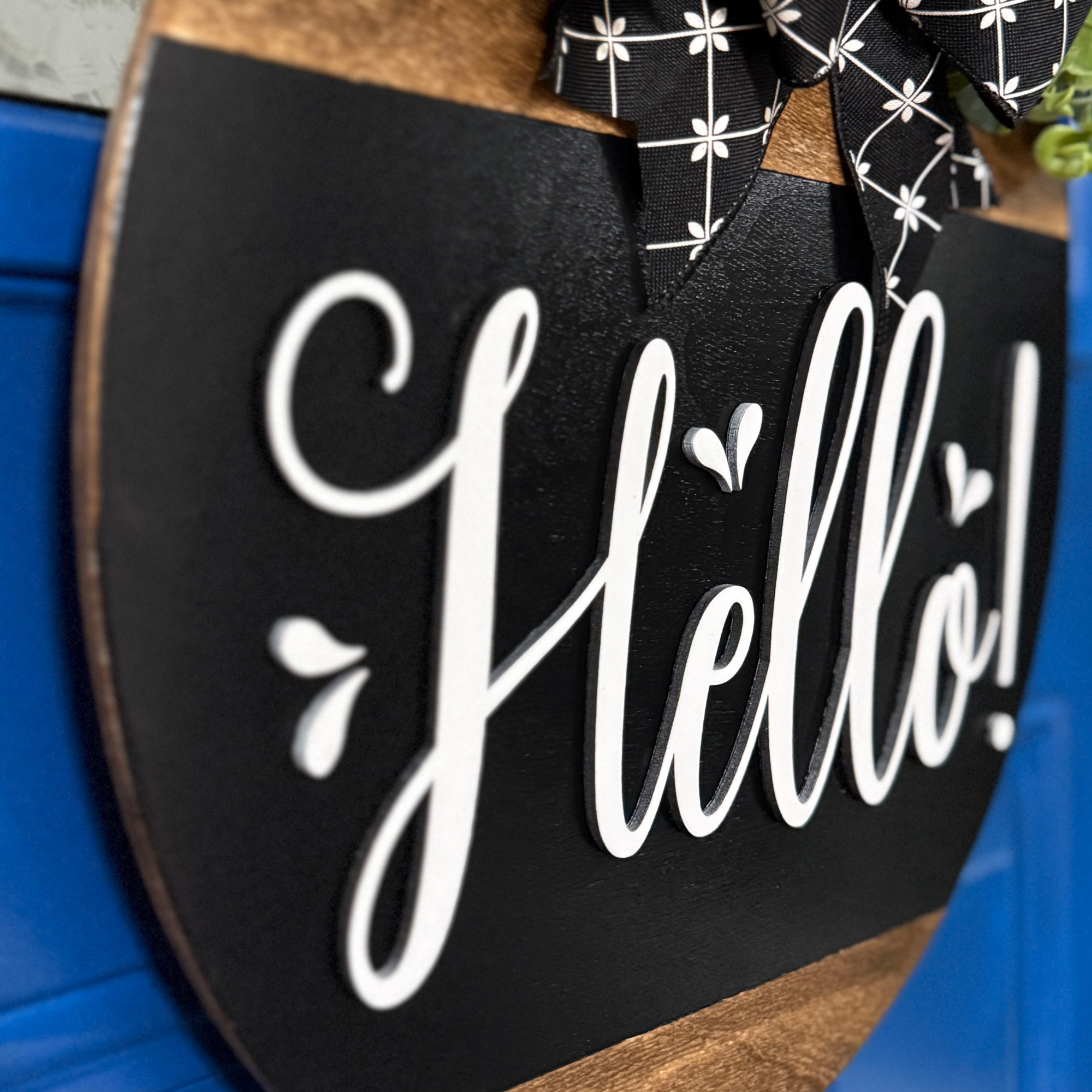 Detailed view of white Hello lettering and natural wood lower section on handcrafted round door hanger