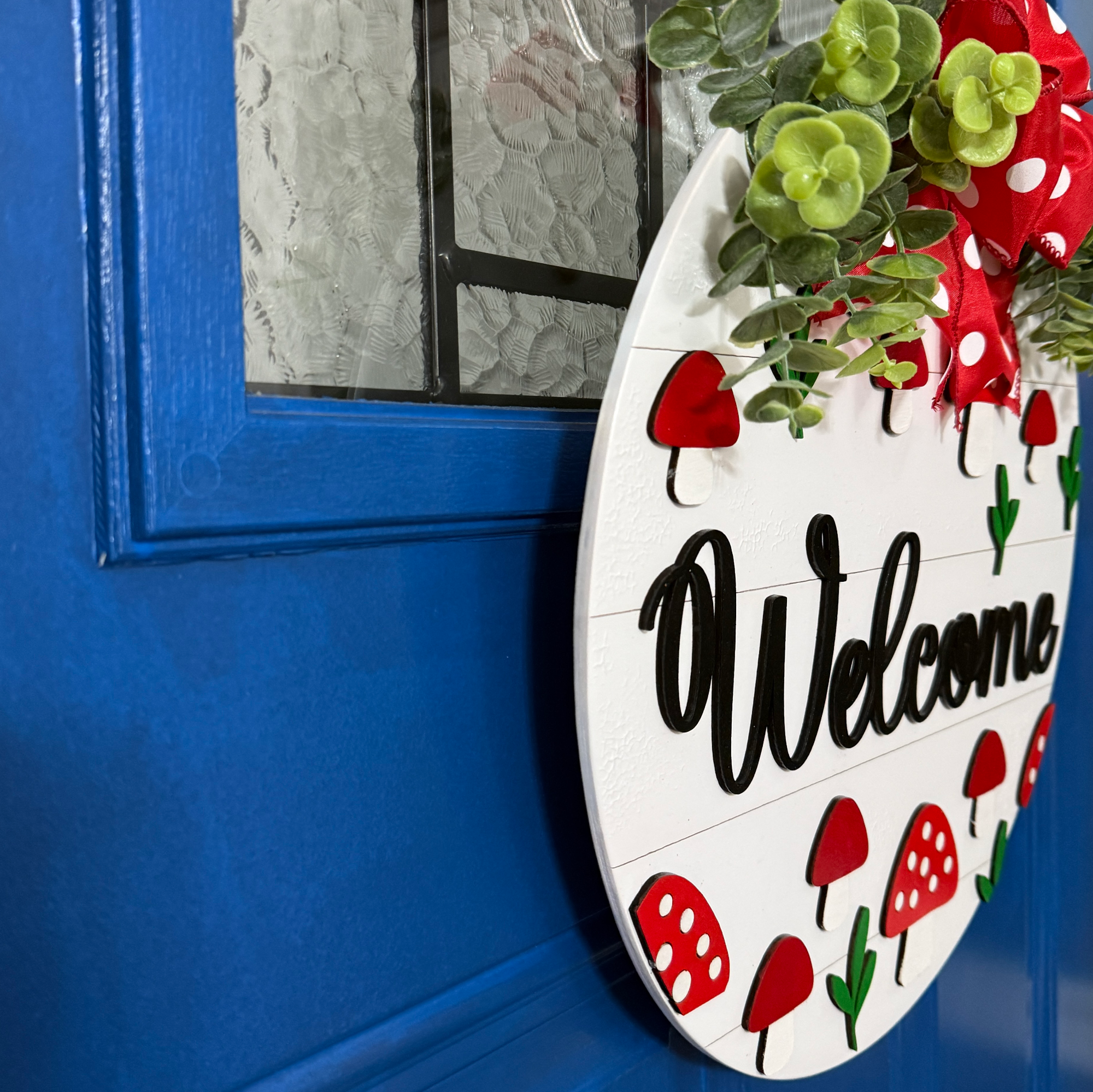 Hand-painted mushroom welcome sign displayed on blue front door