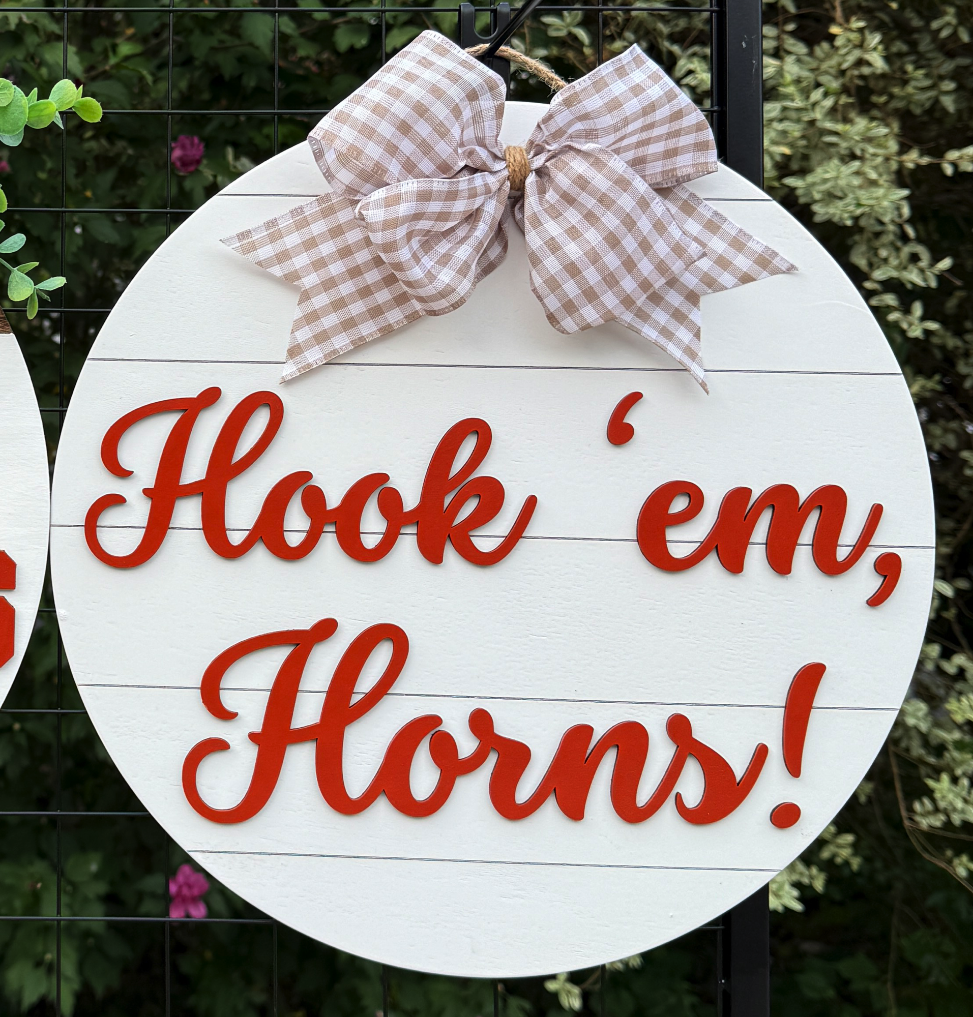 Round Hook ’em Horns door hanger with burnt orange script on white shiplap background and beige gingham bow
