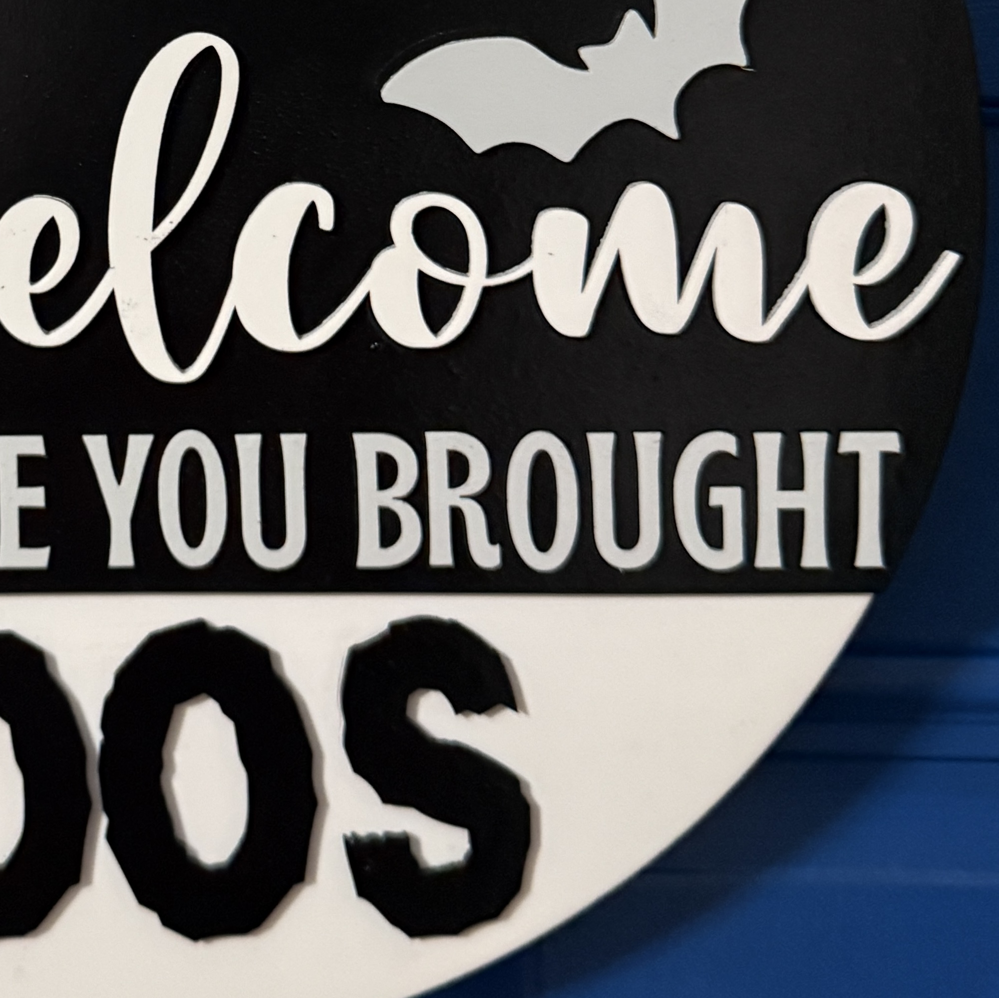 Close-up view of Halloween door hanger highlighting ghost graphic, bats, and buffalo plaid bow