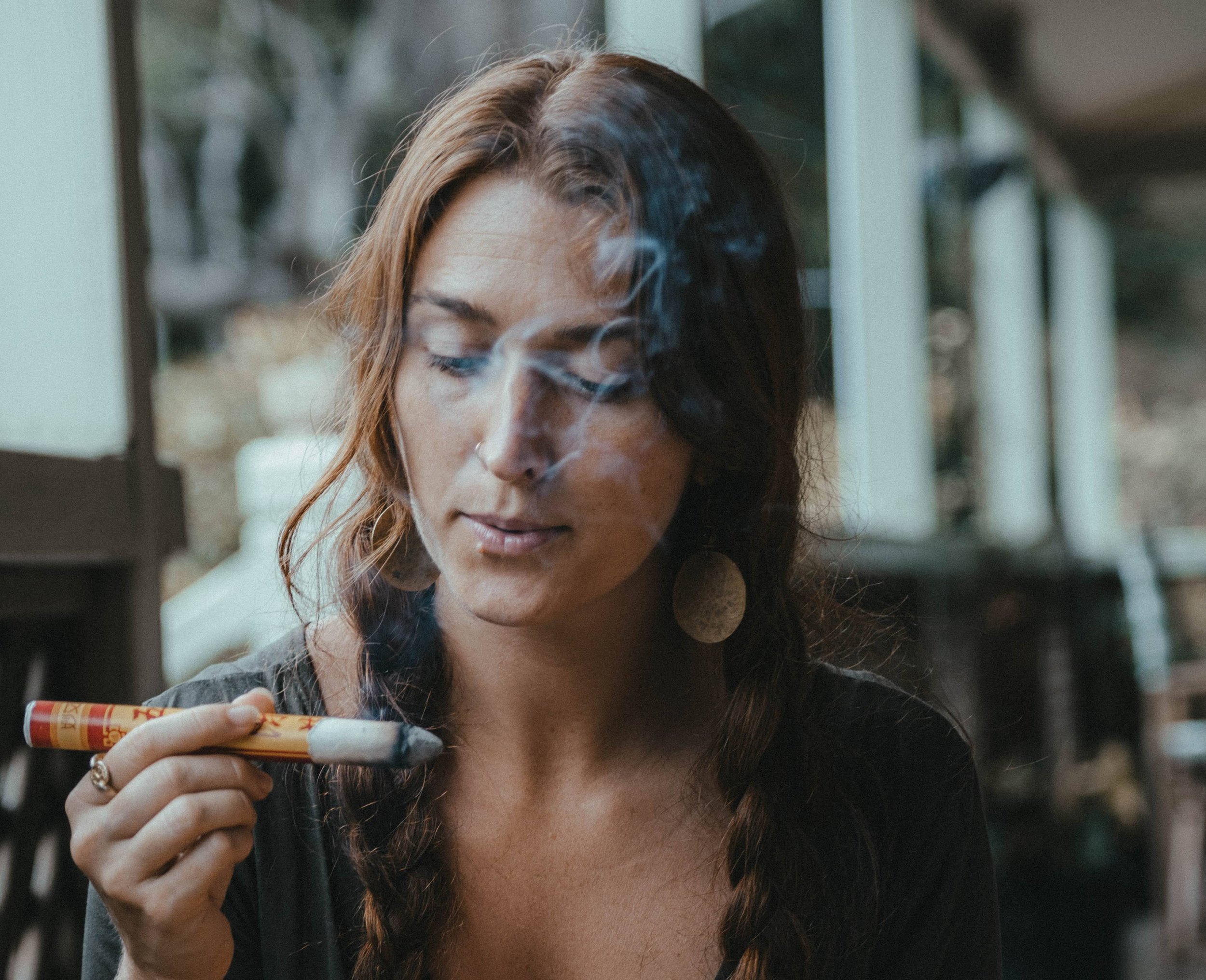 Person holding a smudge stick, releasing smoke