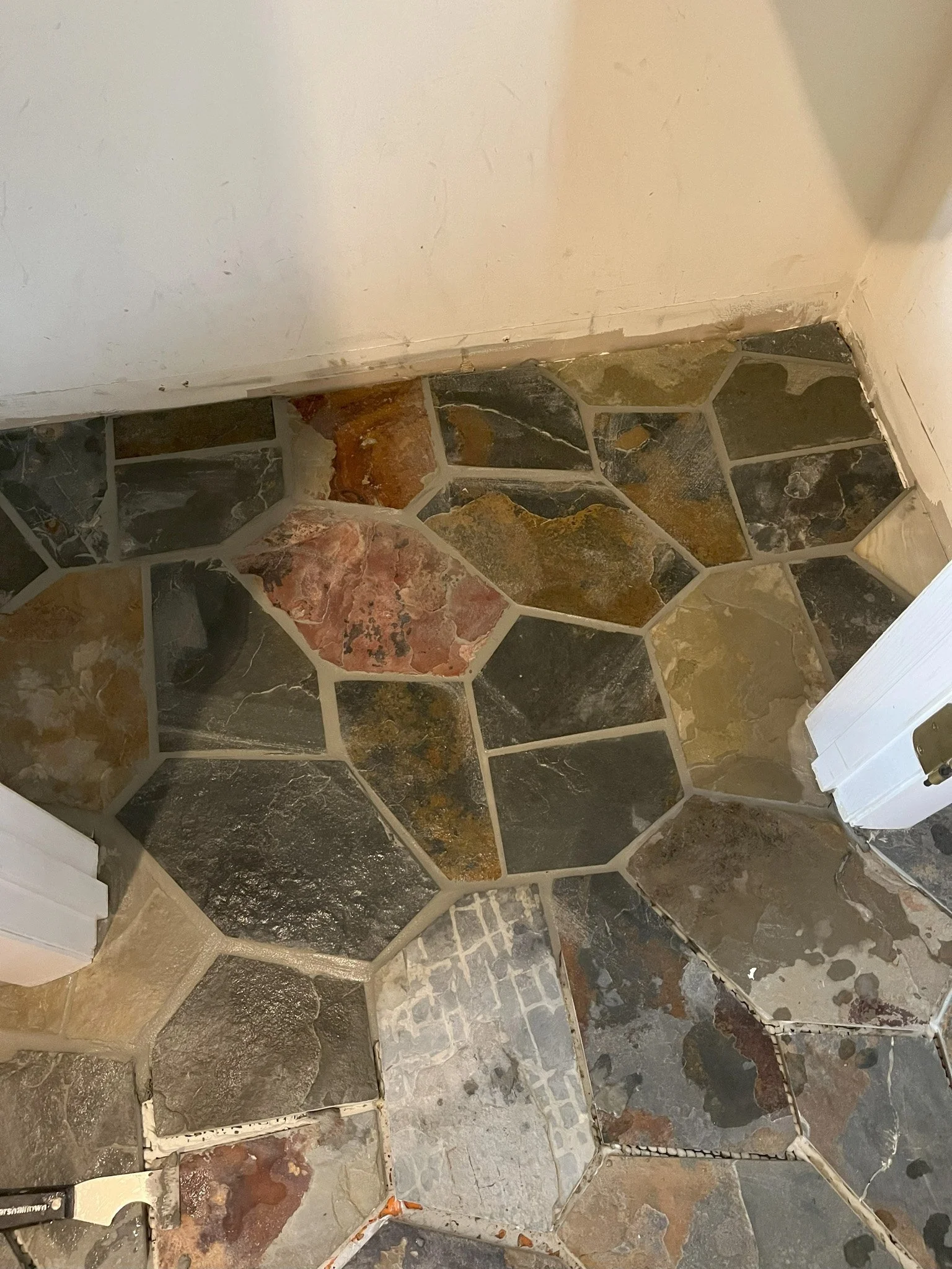 Close-up of a stone tile floor with various shaped and colored stones in shades of brown, gray, black, and pink.