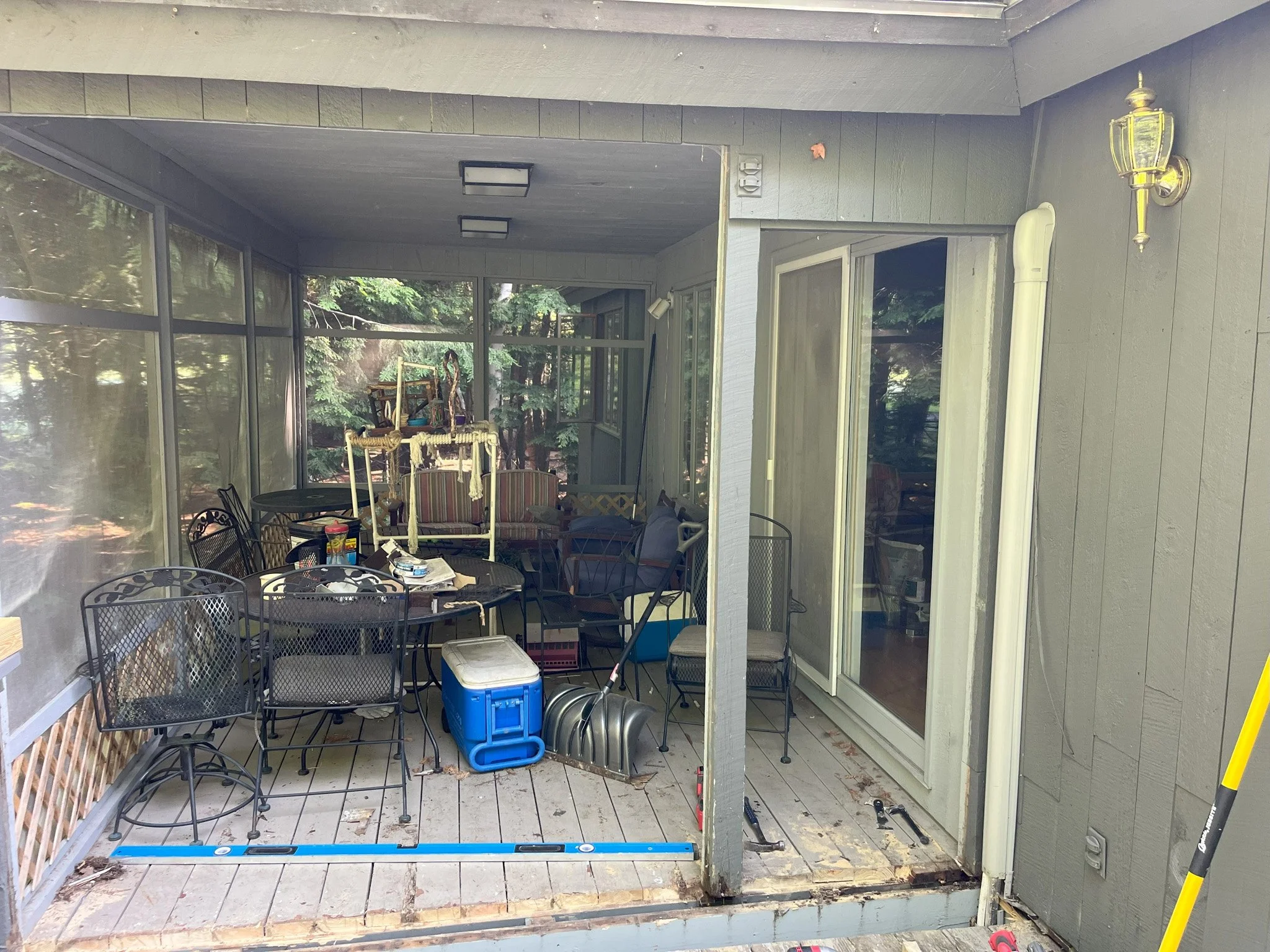 A screened porch with outdoor furniture and various items, partially under renovation.