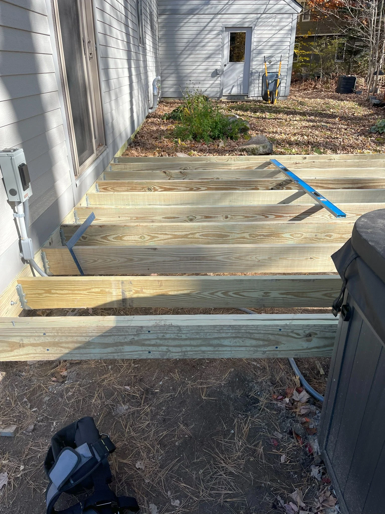 Wooden deck framework construction next to house with a level tool on top