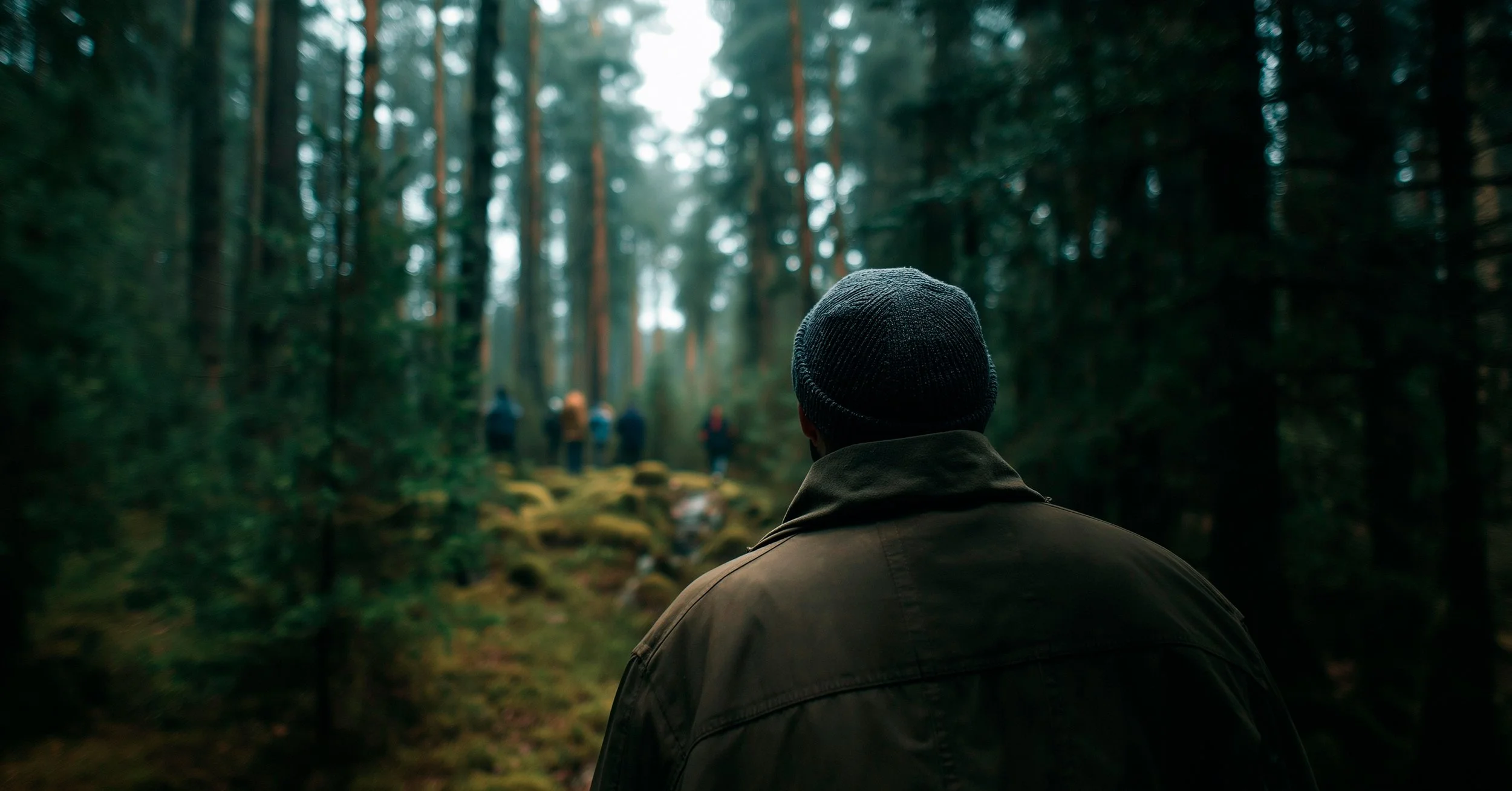 Mies kulkee metsässä väkijoukon perässä