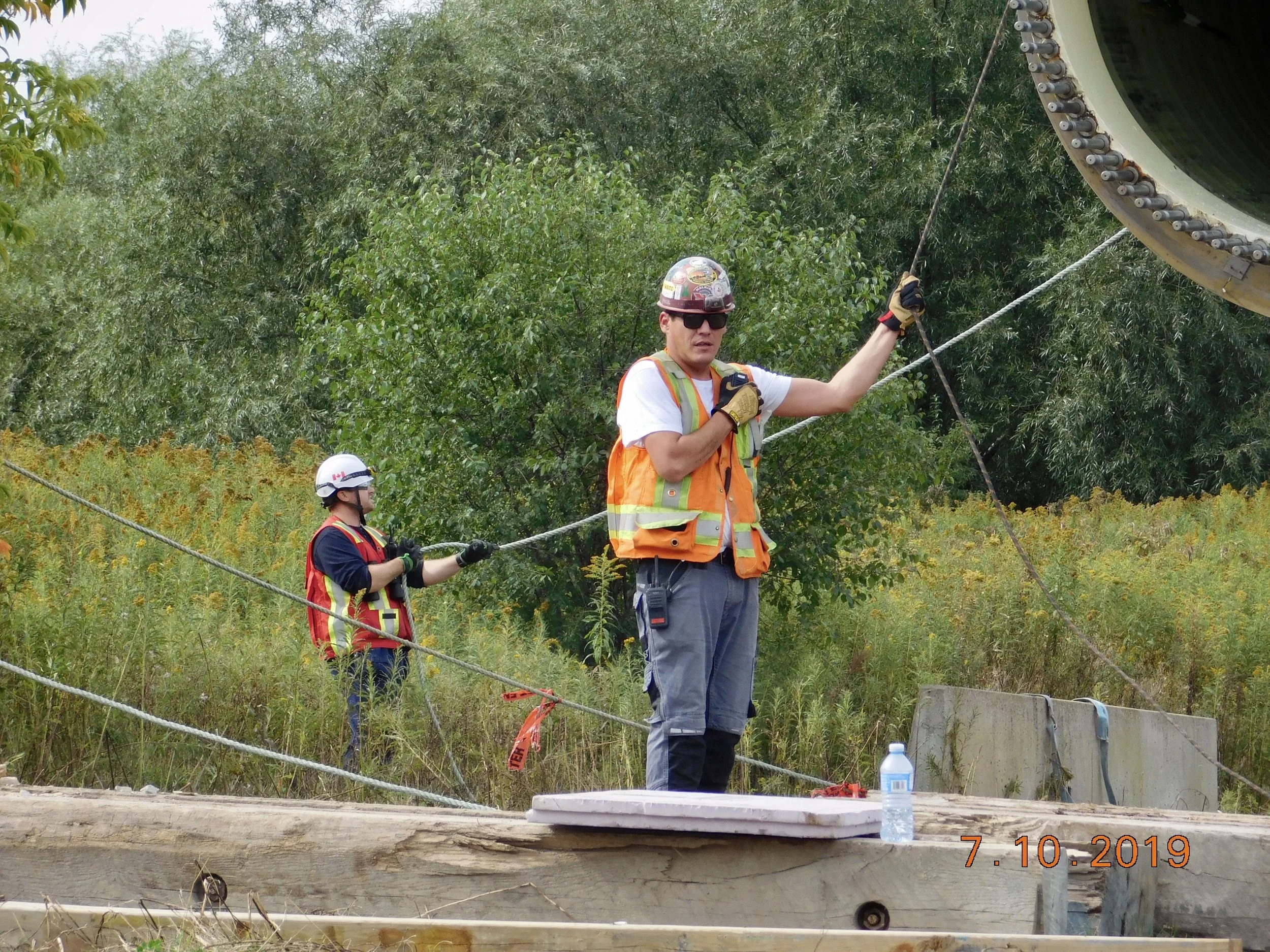Crew in hard hats, safety glasses and hi-vis guiding a lift with tag lines on a wind project