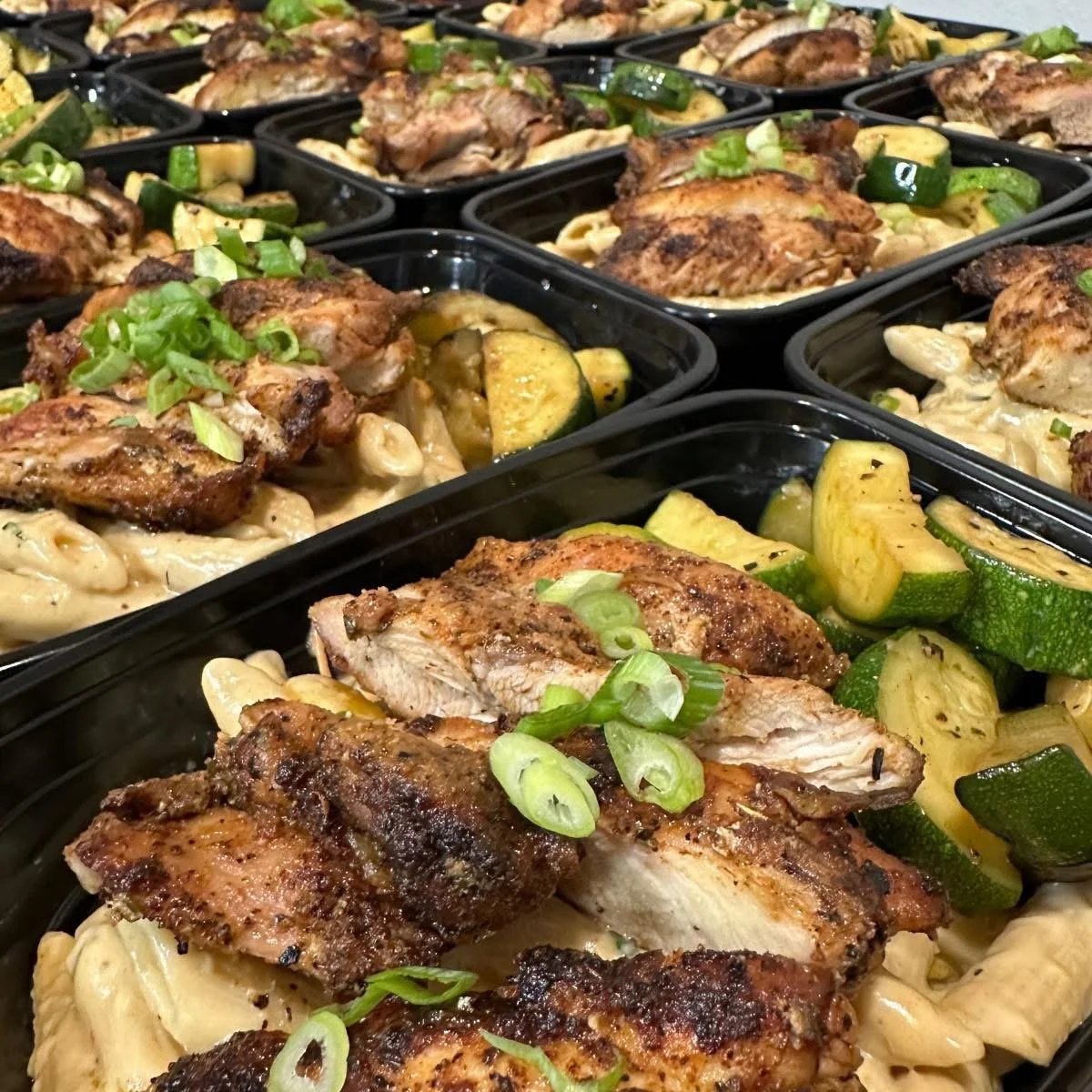 Row of meal prep containers filled with chicken fried rice topped with green onions.