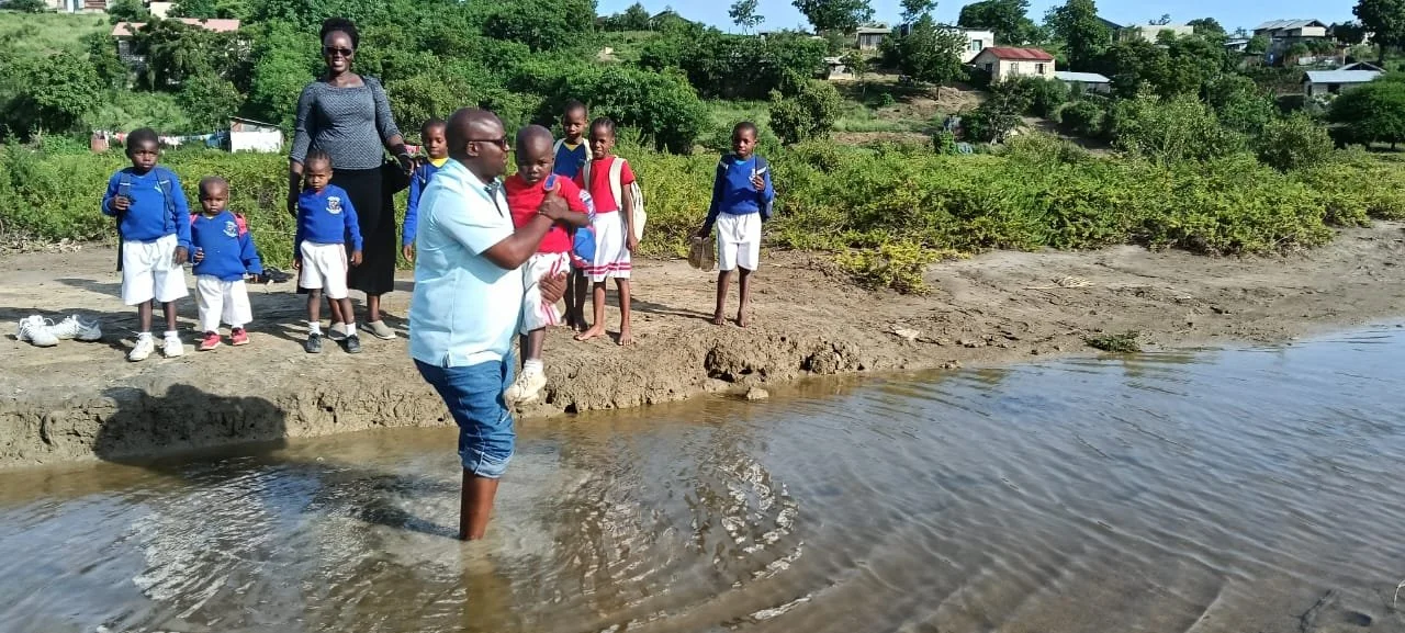 Ken Obuya helping a learner across high water.
