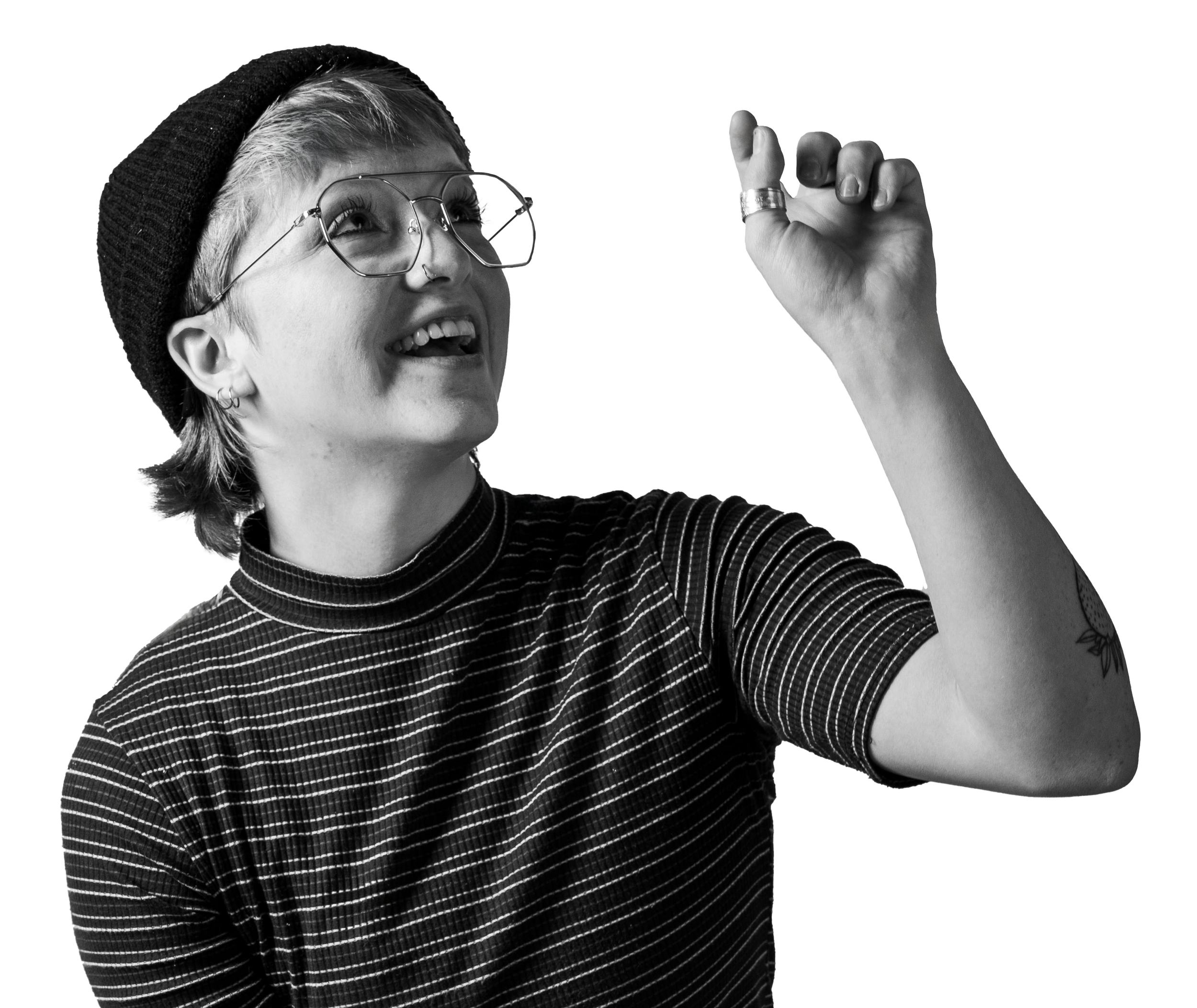 A black and white image of Finn in a black beanie, striped mock neck shirt, and aviator glasses. They're looking up and right smiling, with their left hand reaching up as if to pop a bubble.