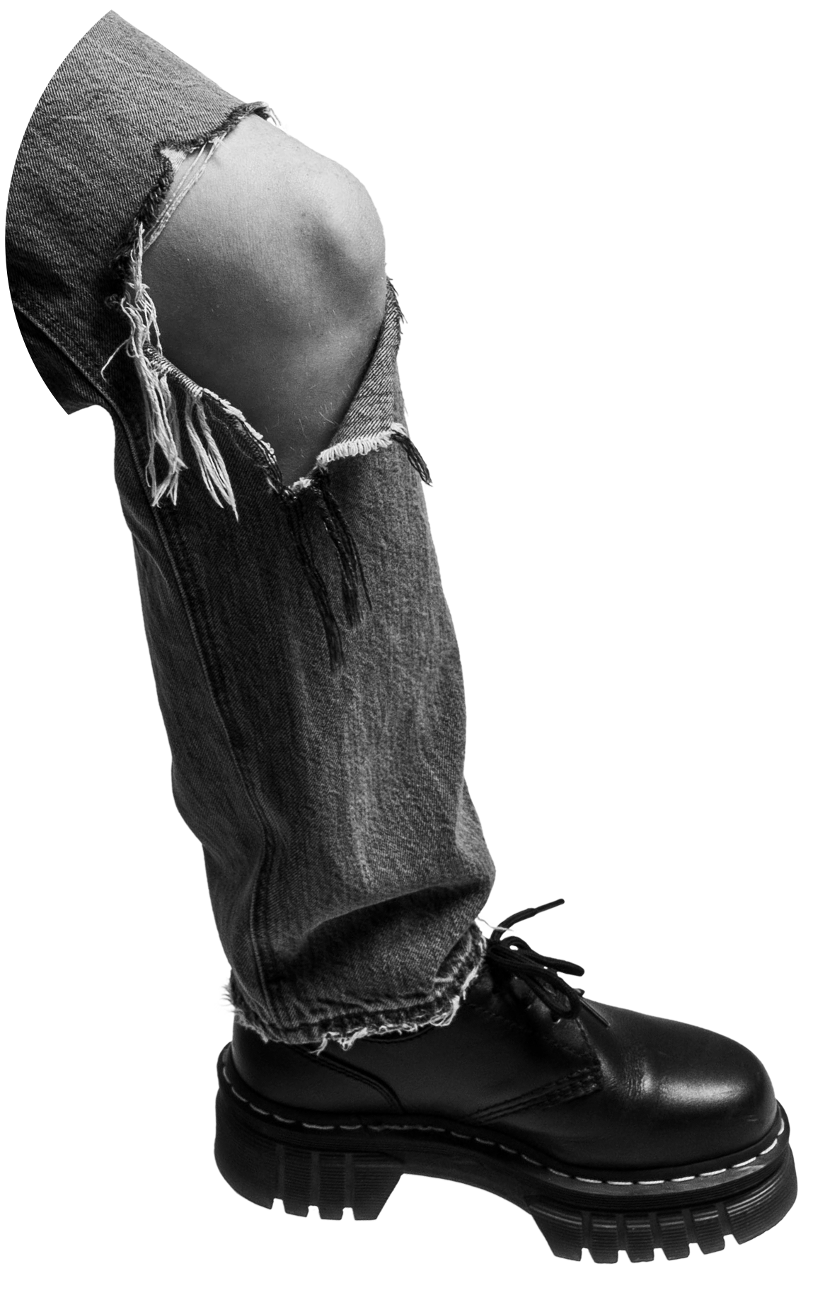 A black and white image of Finn's leg, bent at the knee, wearing jeans ripped at the knee and a black Dr. Marten boot.