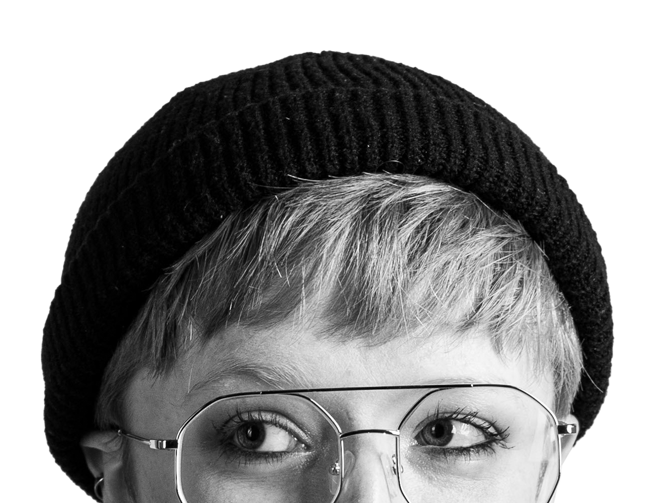 A black and white image of Finn's face from the eyes up, eyes looking left. They're wearing a black beanie and aviator glasses.