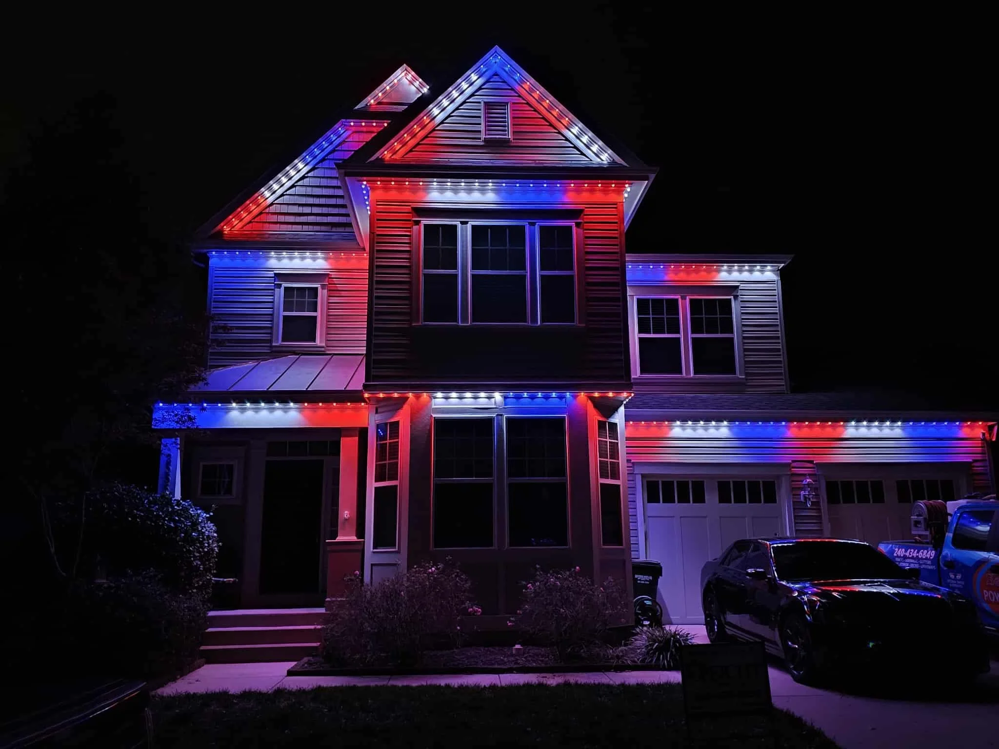 A house decorated with red, white, and blue Christmas lights at night.