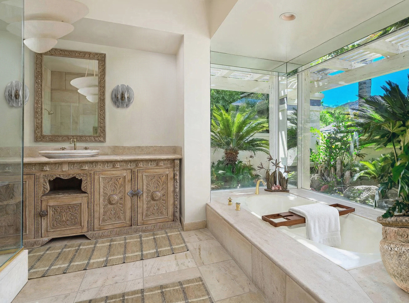 Palm Springs primary bathroom with carved reclaimed wood vanity, brass fixtures, stone vessel sinks, Moroccan influences, soaking tub overlooking courtyard garden, and layered natural plaster finishes.