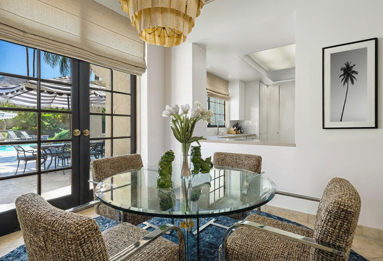 Palm Springs breakfast nook with vintage glass table, woven chairs, mid-century chandelier, French doors opening to patio, and soft organic desert palette.