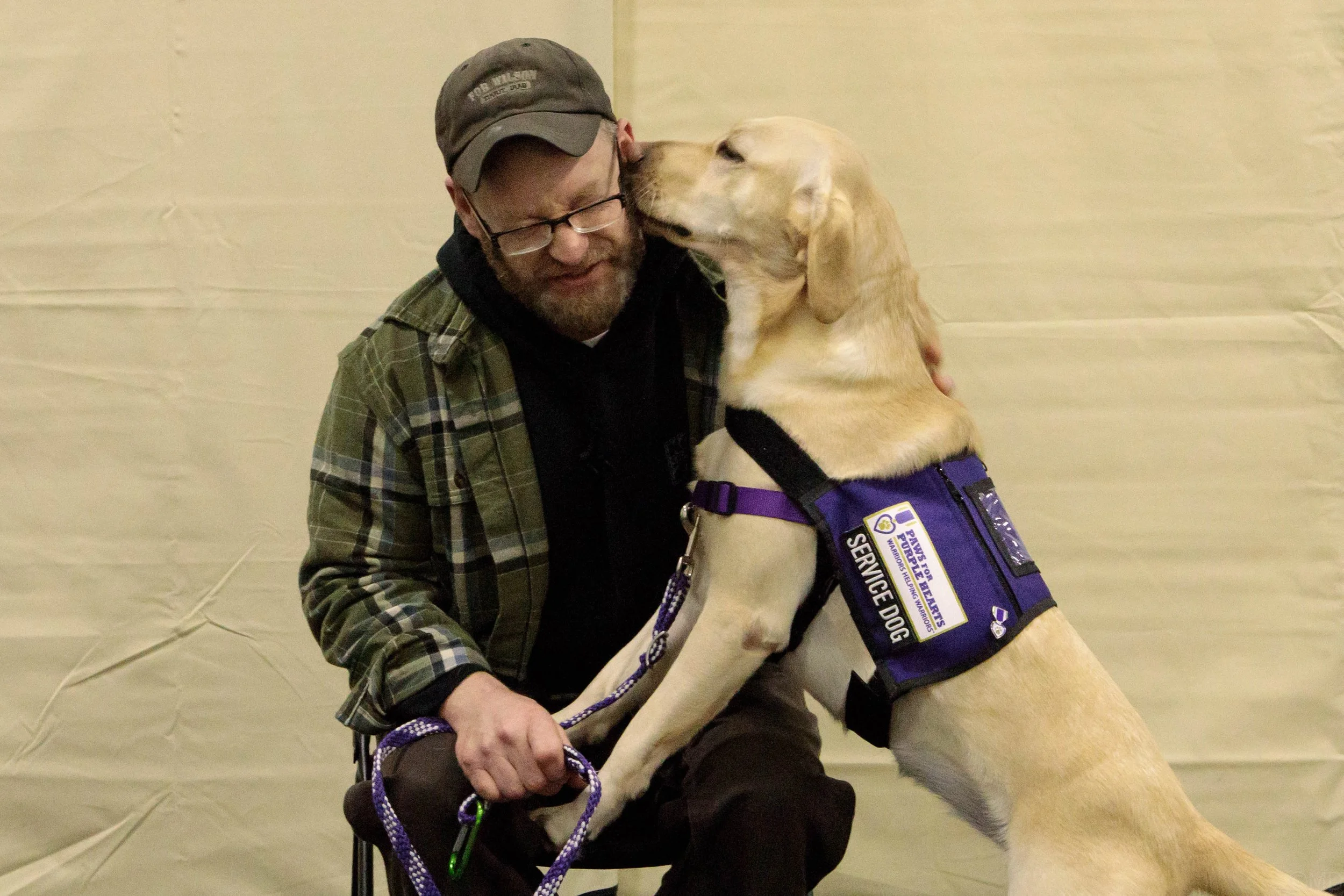 A dog kissing a veteran