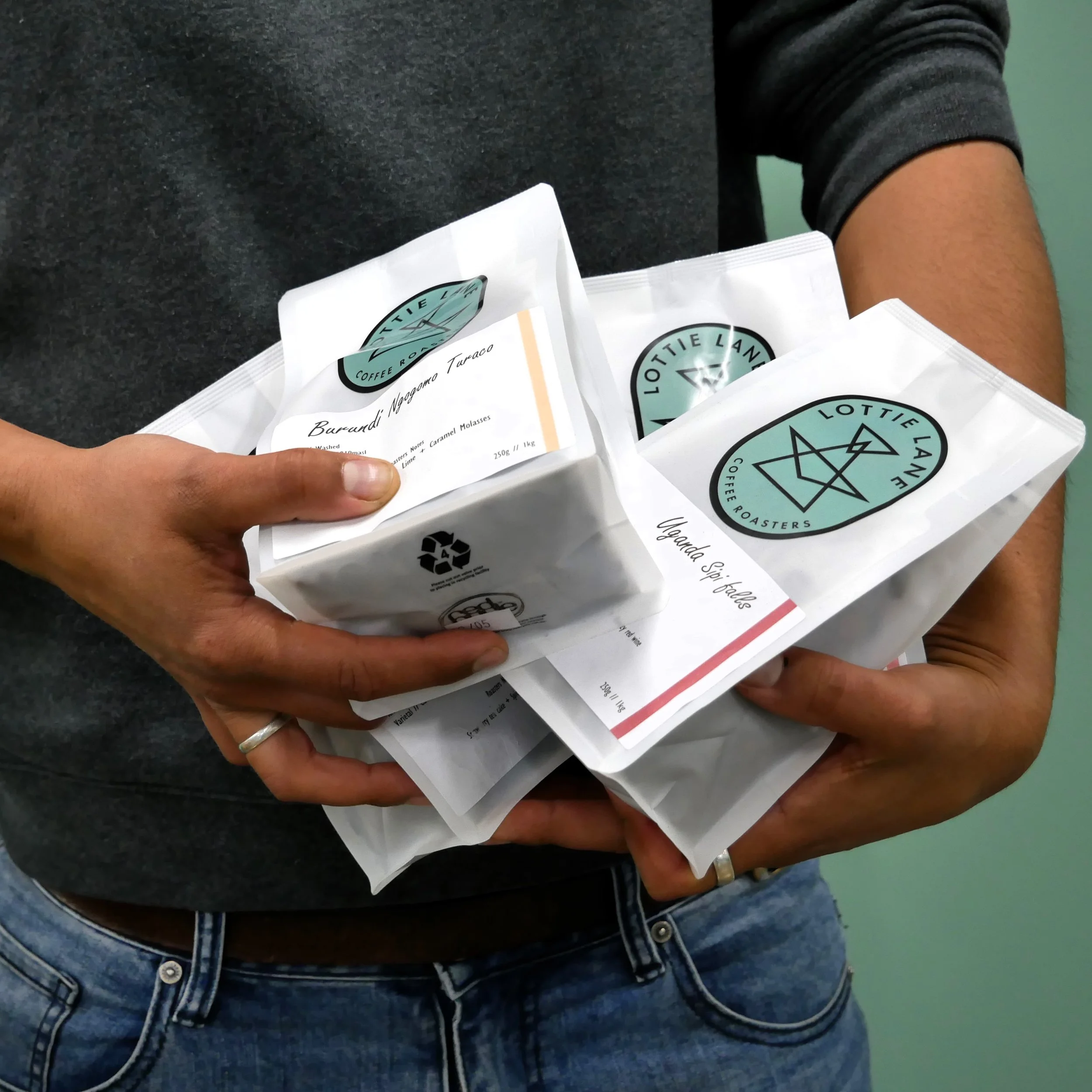 A person holding different bags of coffee beans.