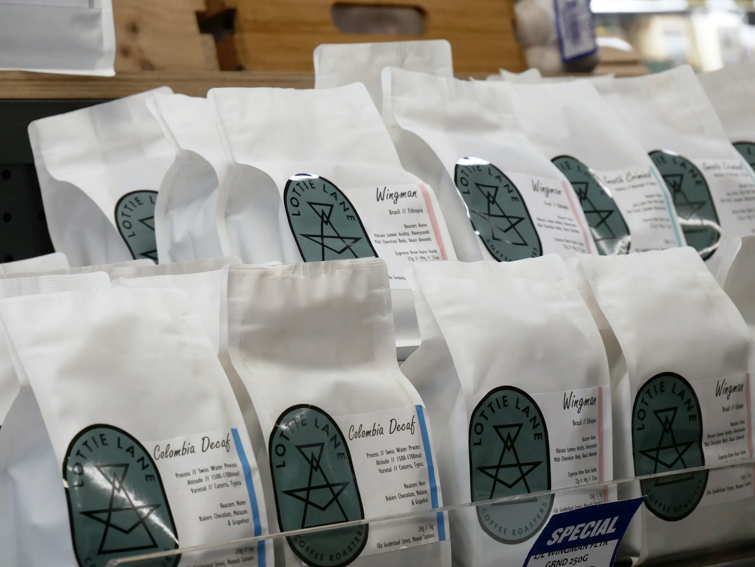 Rows of white coffee bags with black logos and labels on shelves in a coffee shop or store.