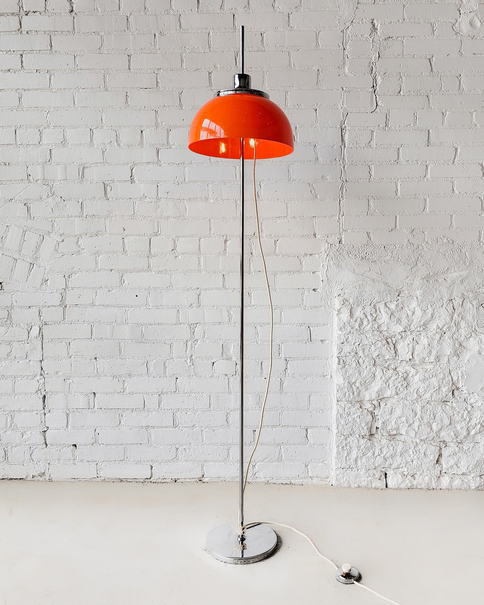 This vintage Faro floor lamp by Luigi Massoni (for Harvey Guzzini, produced by Meblo in 1970s Yugoslavia) brings bold space-age energy to any corner it lights up. With its vibrant orange acrylic shade and gleaming chrome base, this piece is pure retr