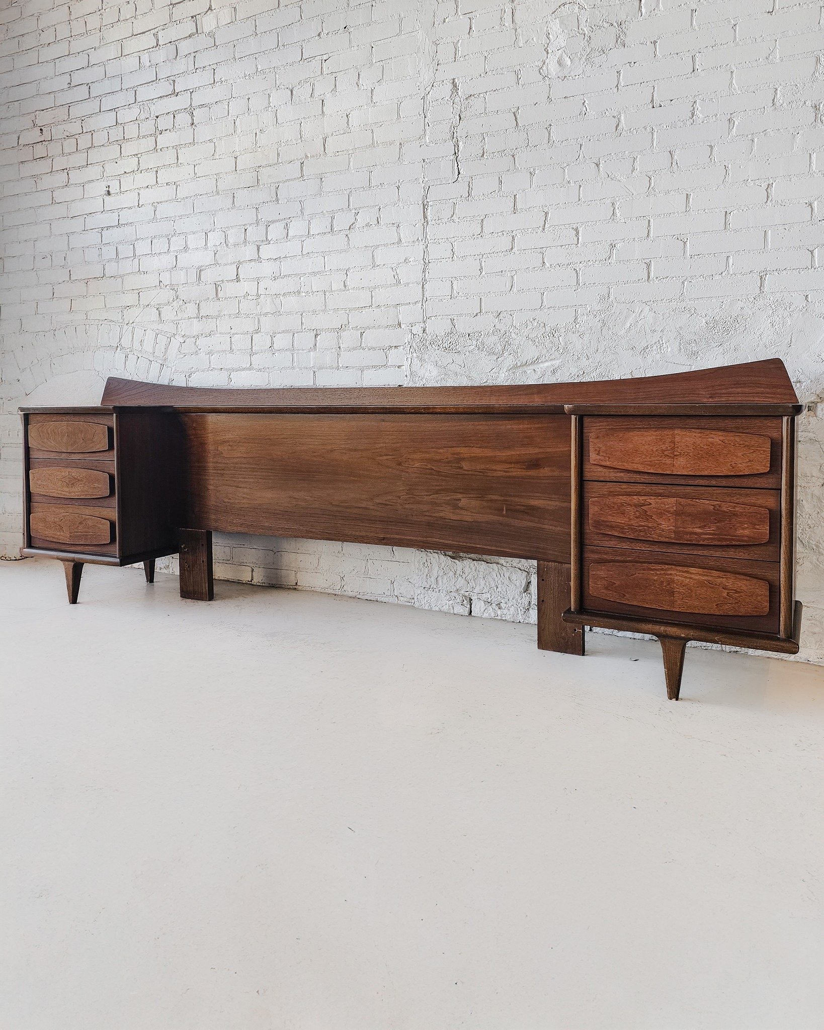 This rare American of Martinsville walnut queen headboard is a showstopper—sleek, sculptural, and packed with function. Designed with that iconic mid-century flair, it features deep walnut tones and signature sculpted oblong pulls that instantl