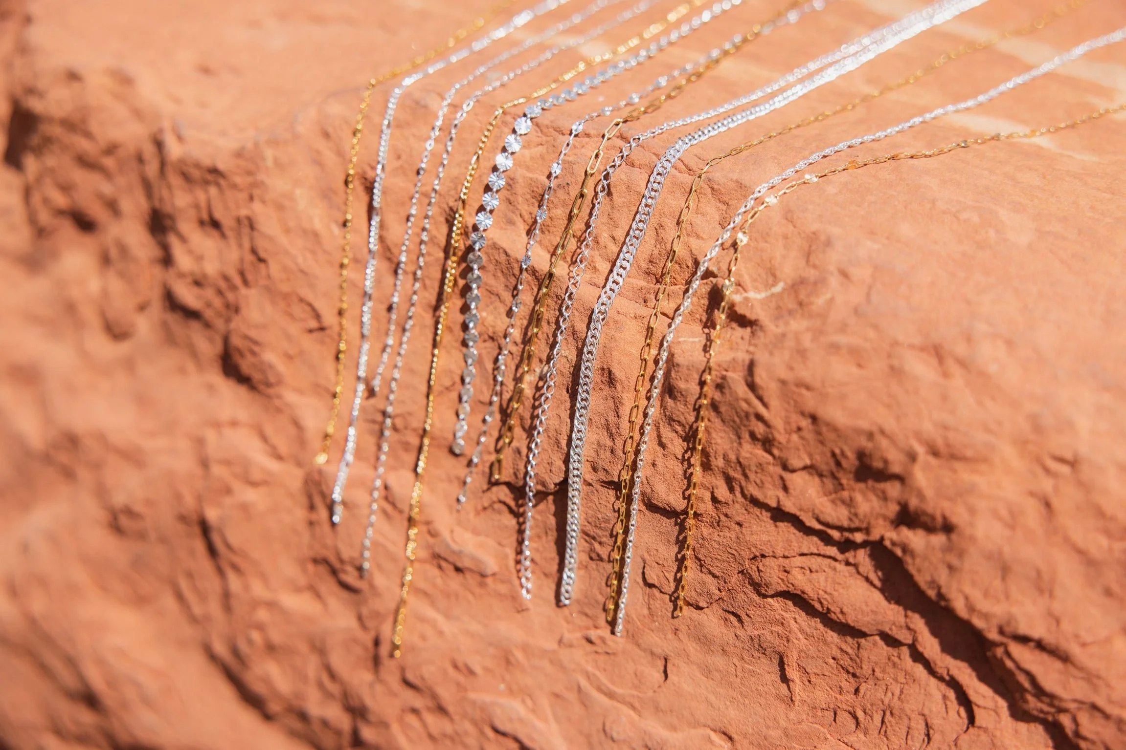 Sterling silver and 14k gold-filled permanent jewelry chains on red rock in St. George, Utah