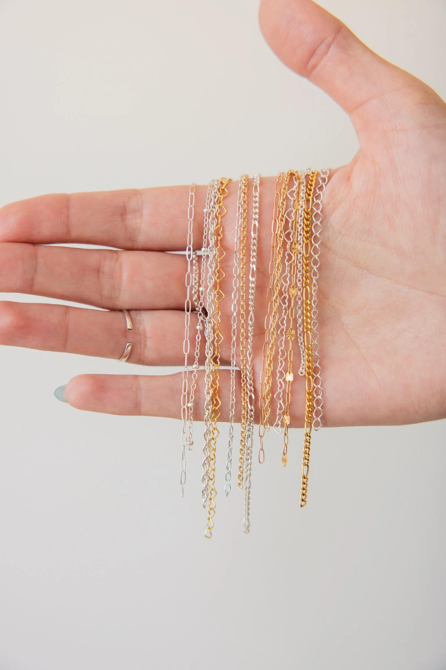 Hand holding draped gold and silver chains