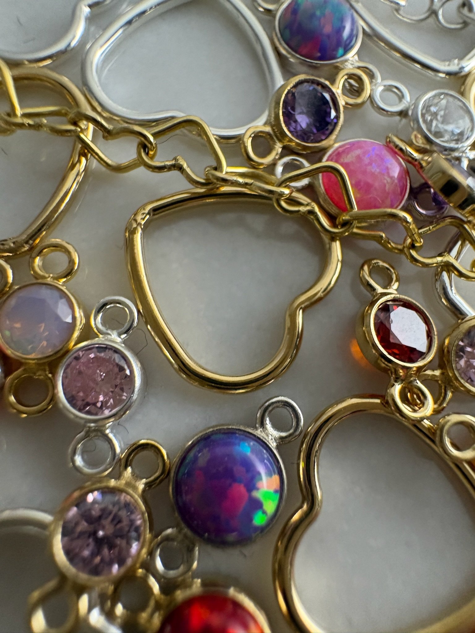 Heart-shaped gold charms with pink and purple birthstones