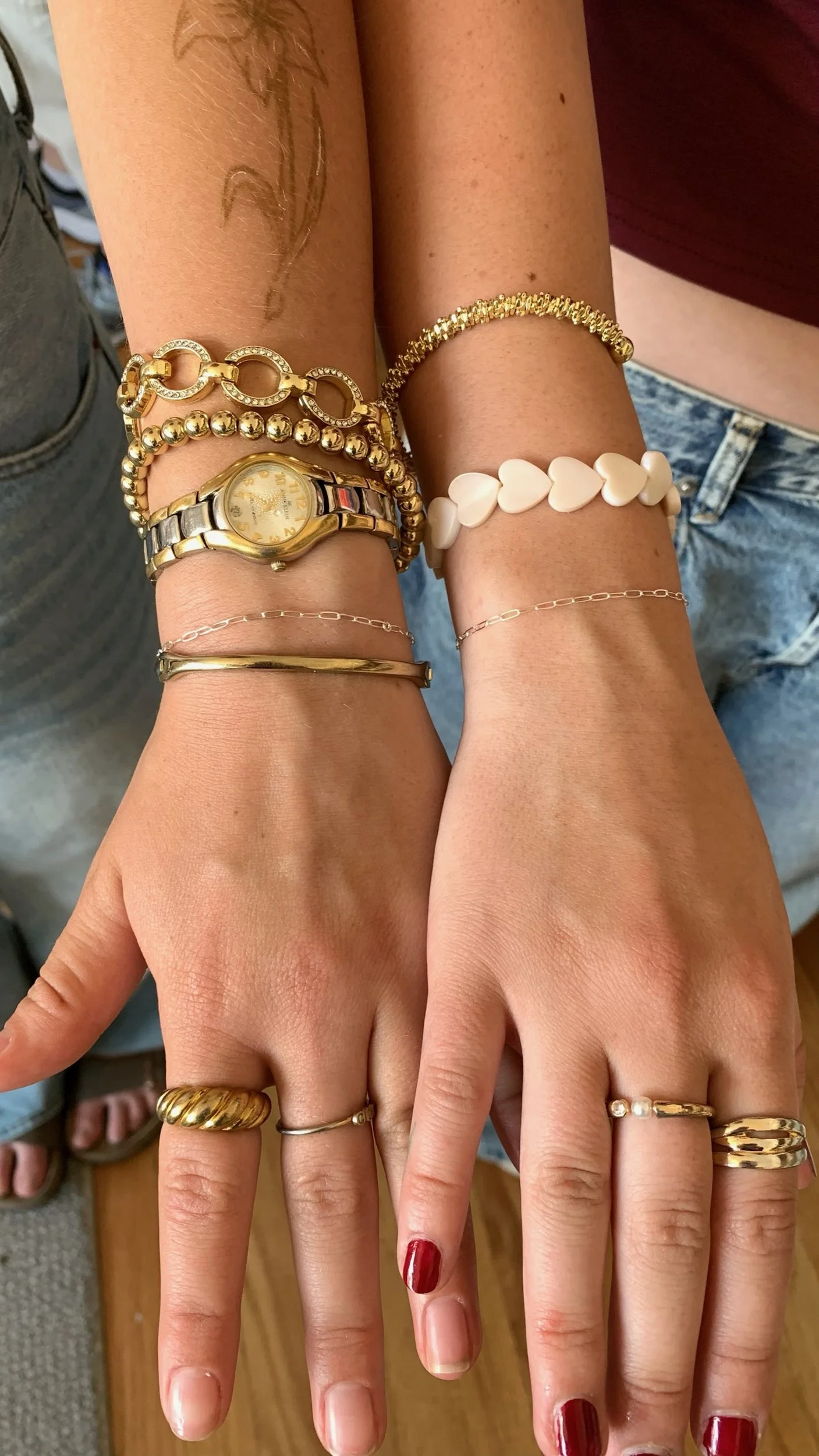 Hands wearing a stack of layered gold bracelets and rings