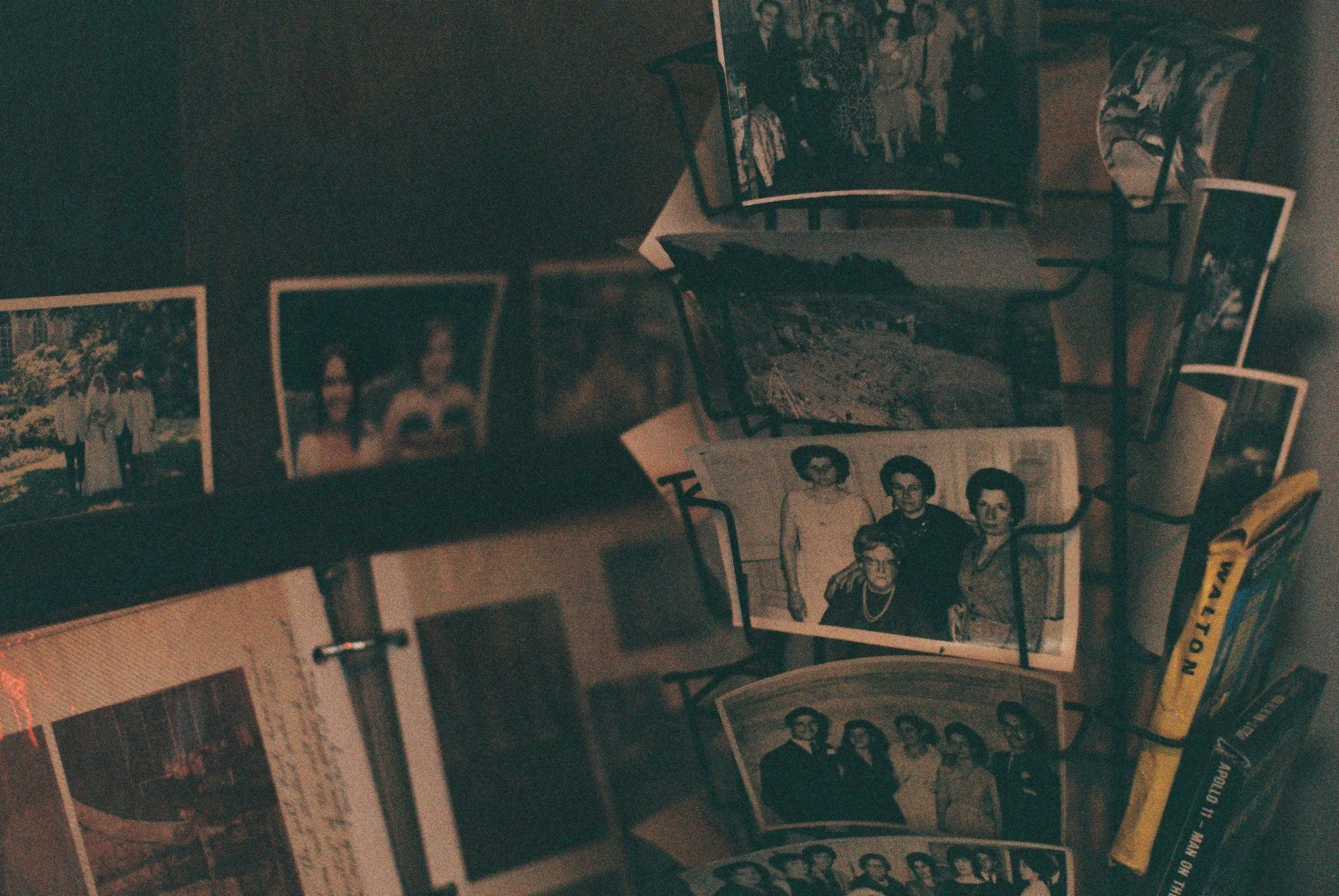 a wire spinning rack is to the right with one side holding paperback books and the other holding black and white family photos. To the left are more old photographs