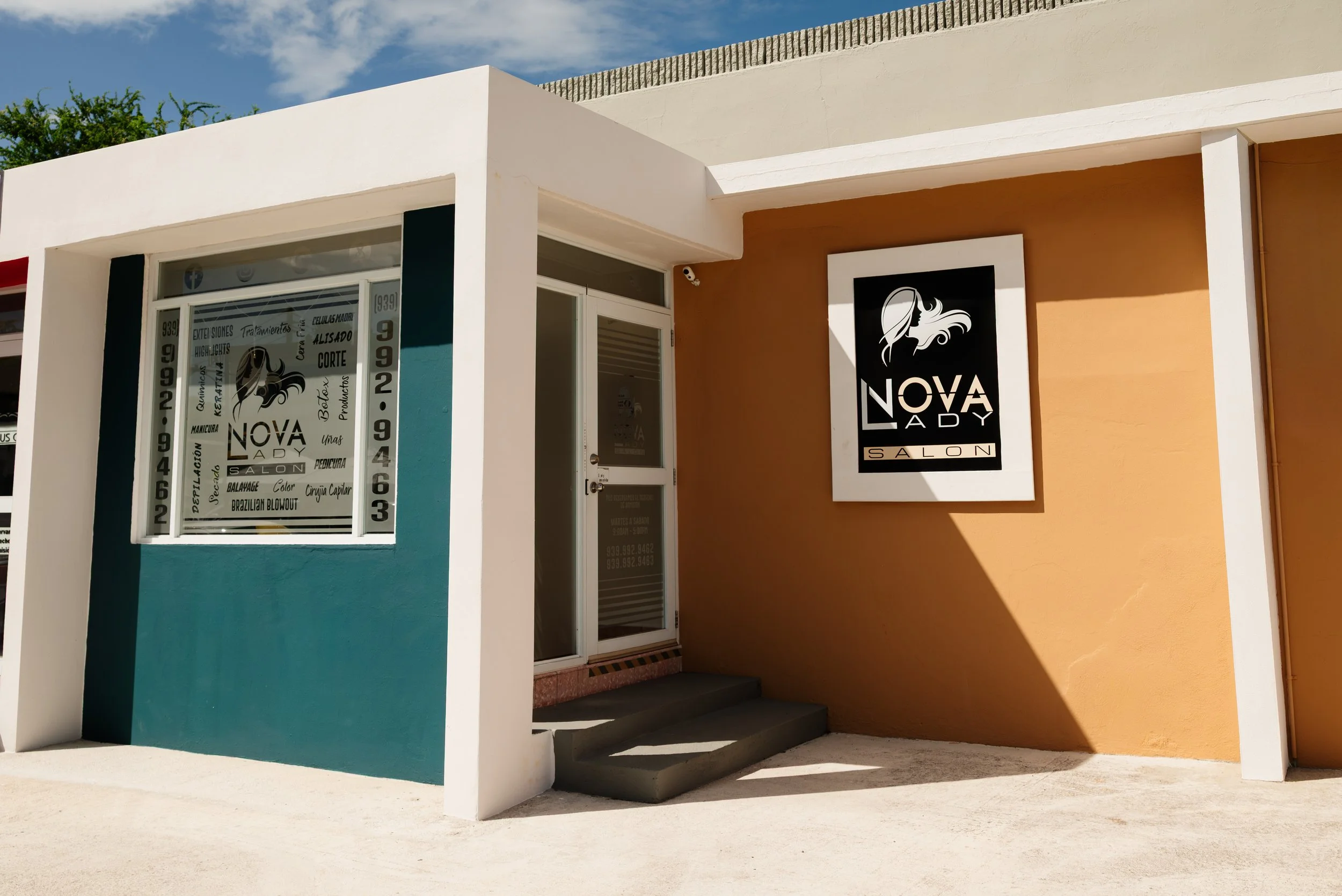 Exterior of a modern salon building with a black and white logo sign, colorful walls, glass door, and window display.