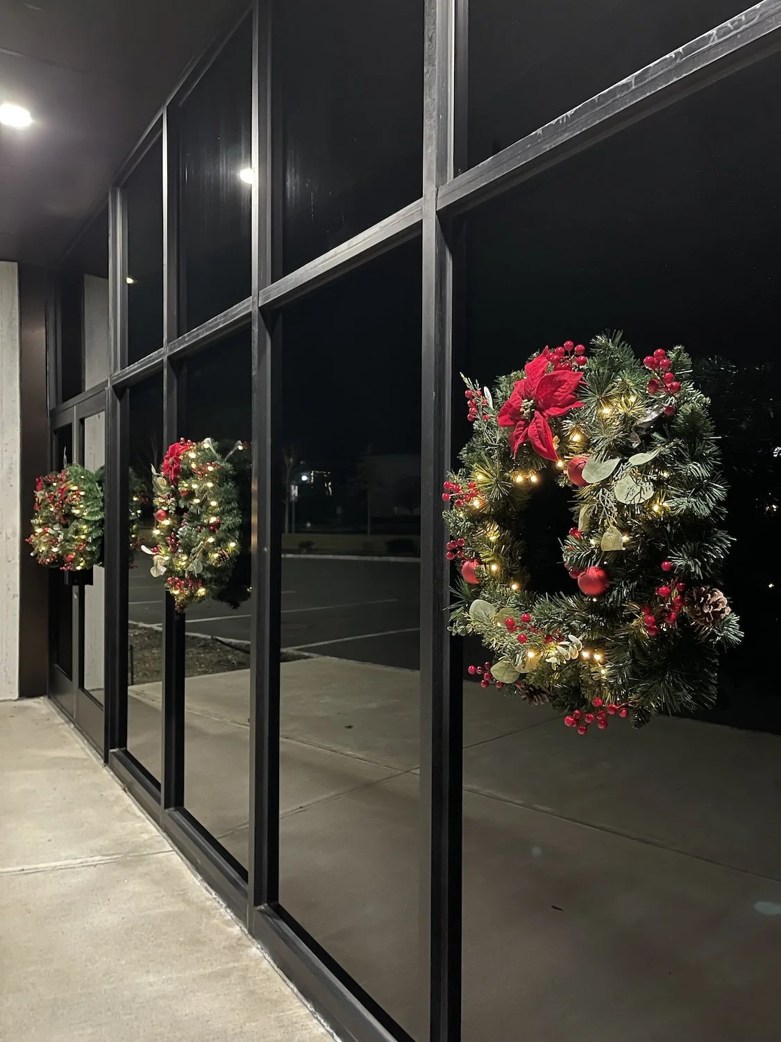 A commercial space decorated with pre-lit wreaths for Christmas.