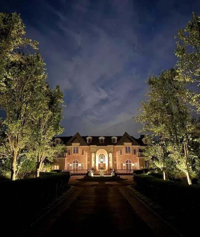 Landscape lighting installation in Oyster Bay, NY featuring spotlights and path lights illuminating the home’s exterior