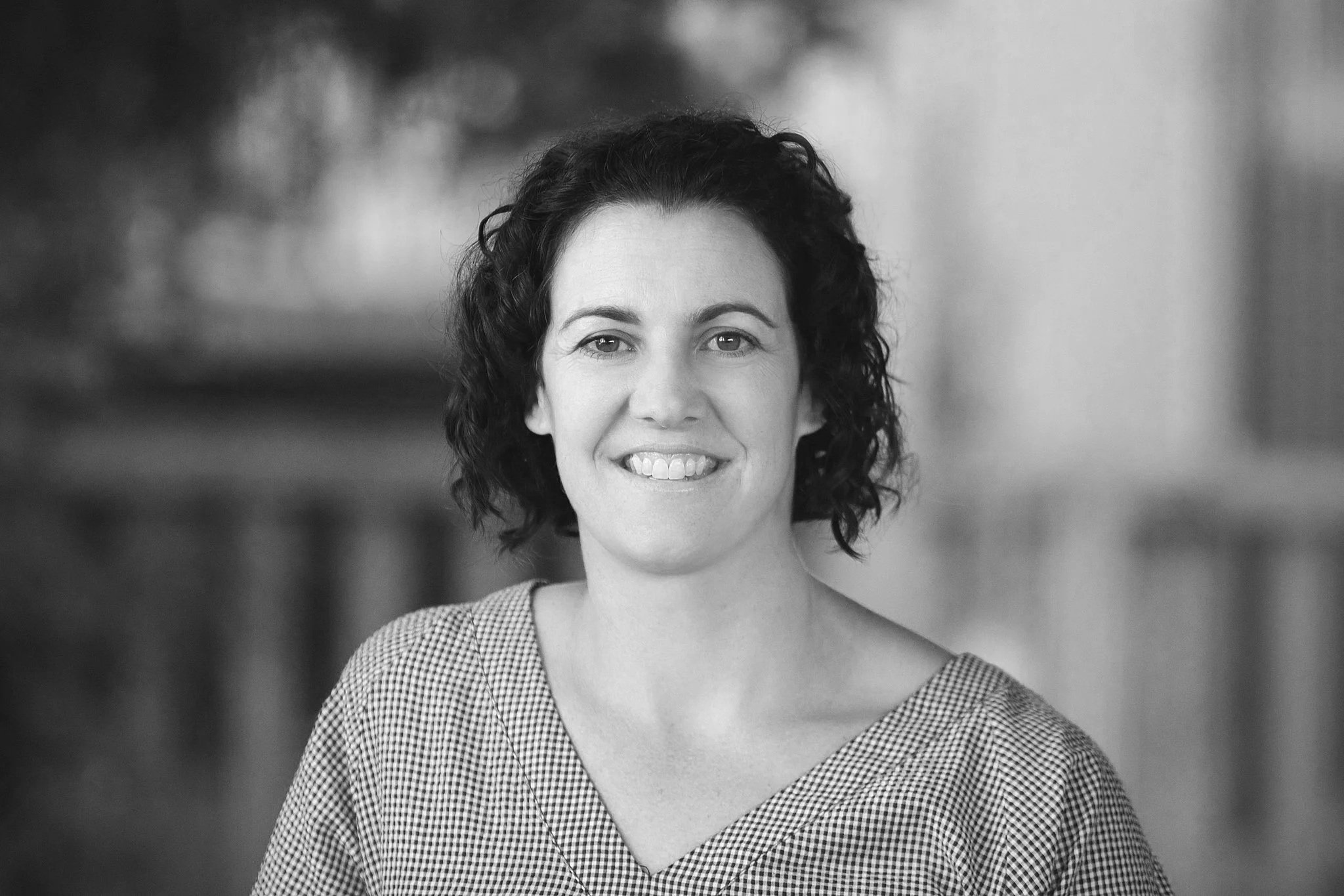 photo of louise benns leaning on a fence with a herd of cows behind her