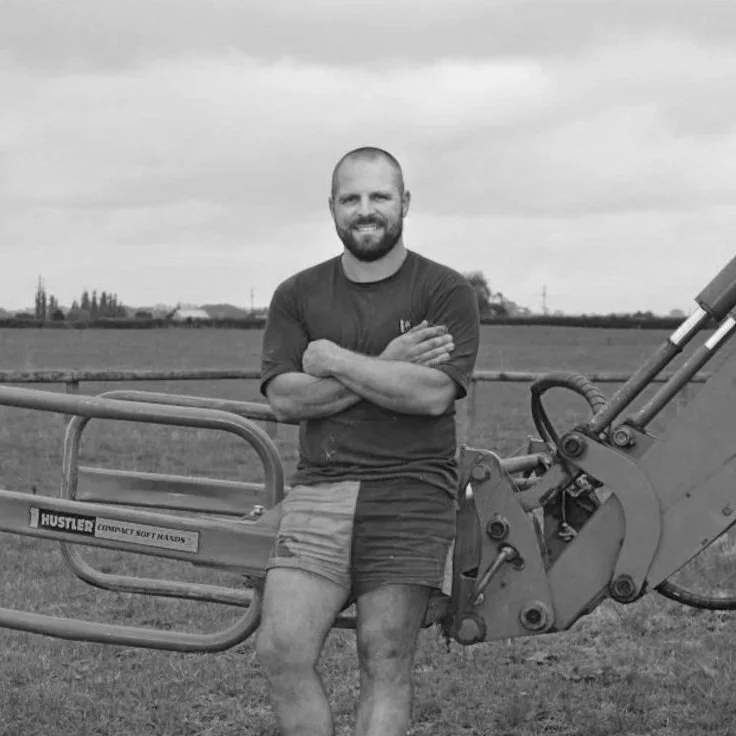 photo mark benns leaning against some machinery on a farm