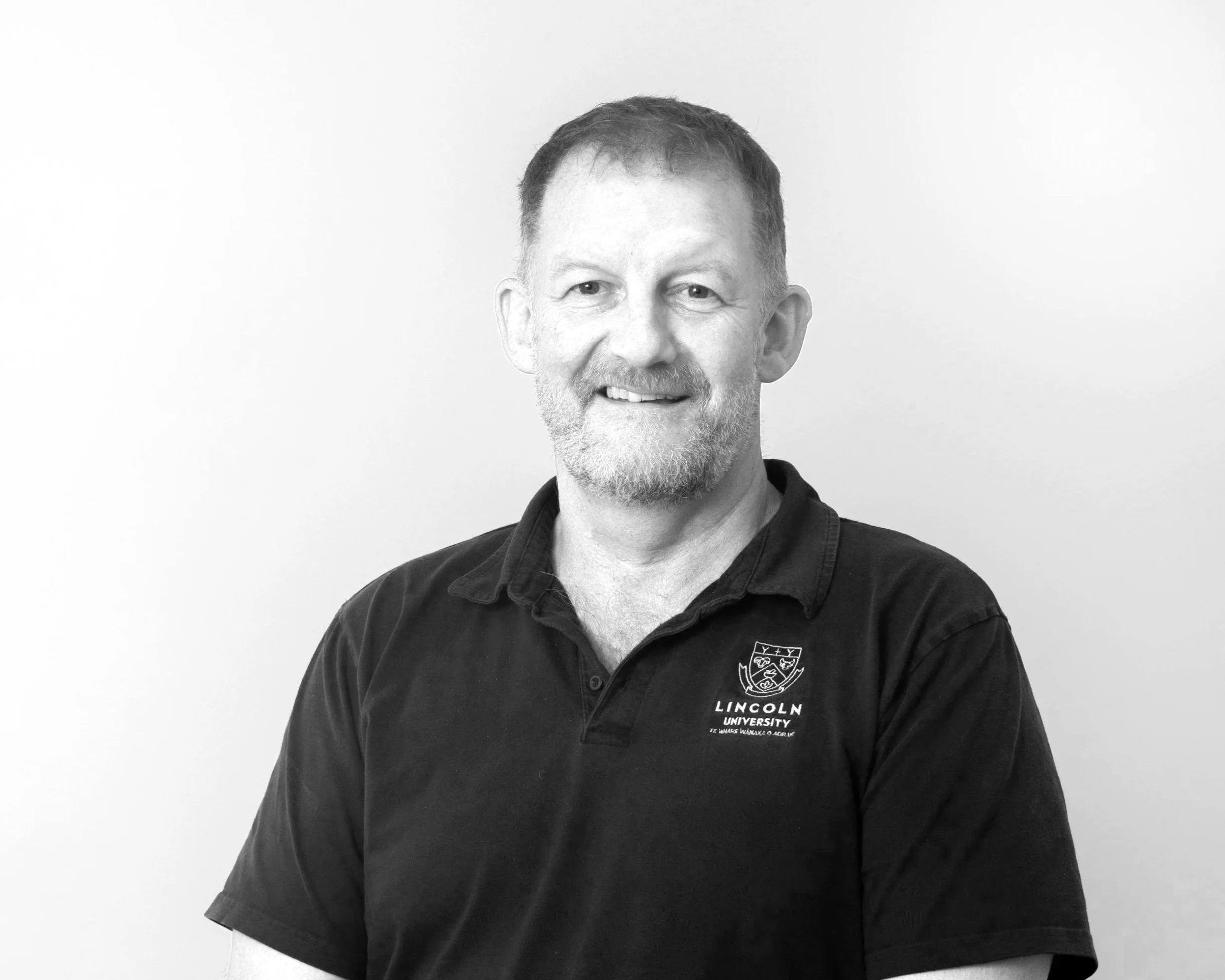 photo of hamish gow in business clothes standing near a fence on a farm