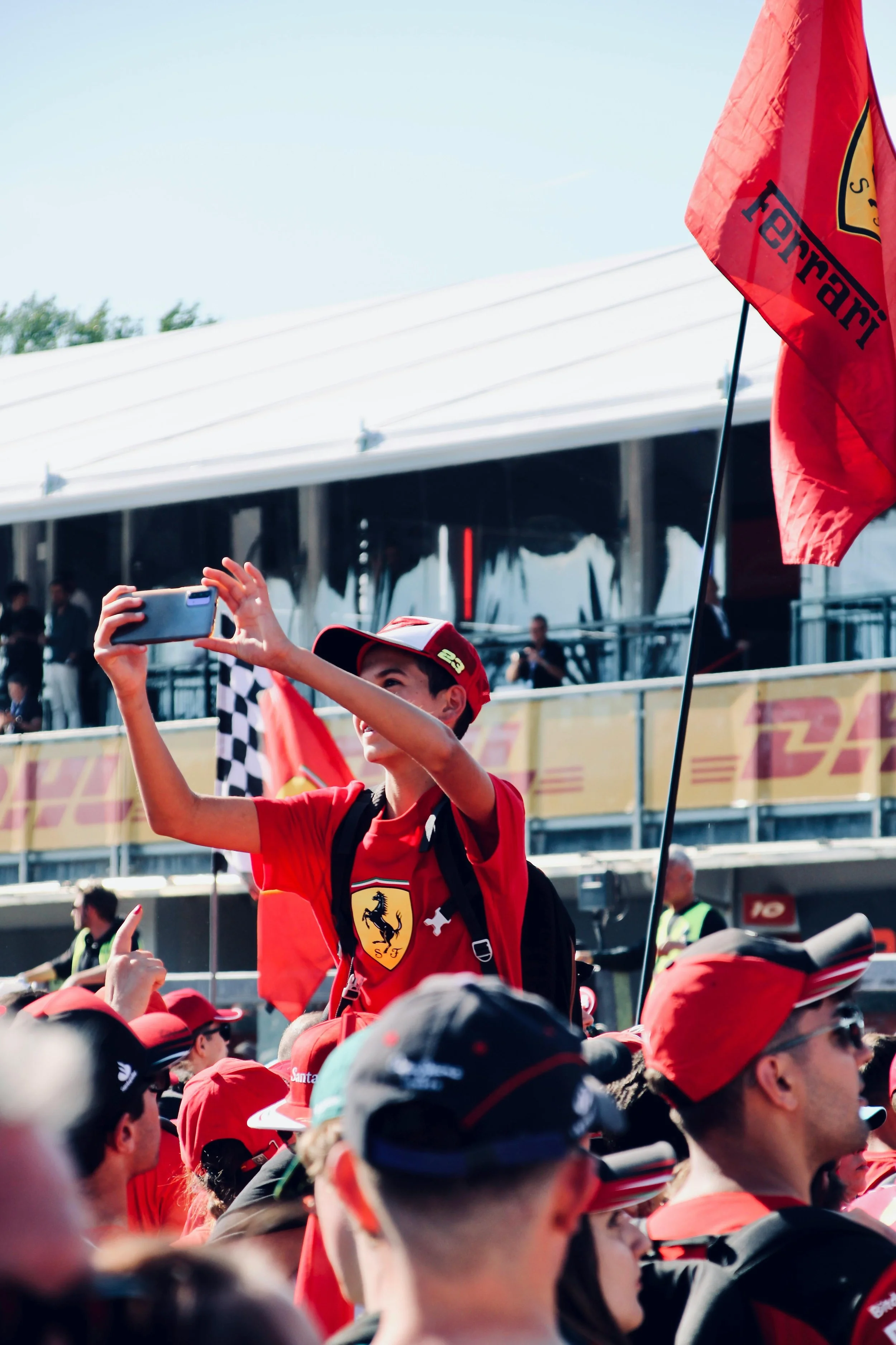Formula 1 fan capturing race moment on phone, representing modern fan engagement and content-driven F1 experience