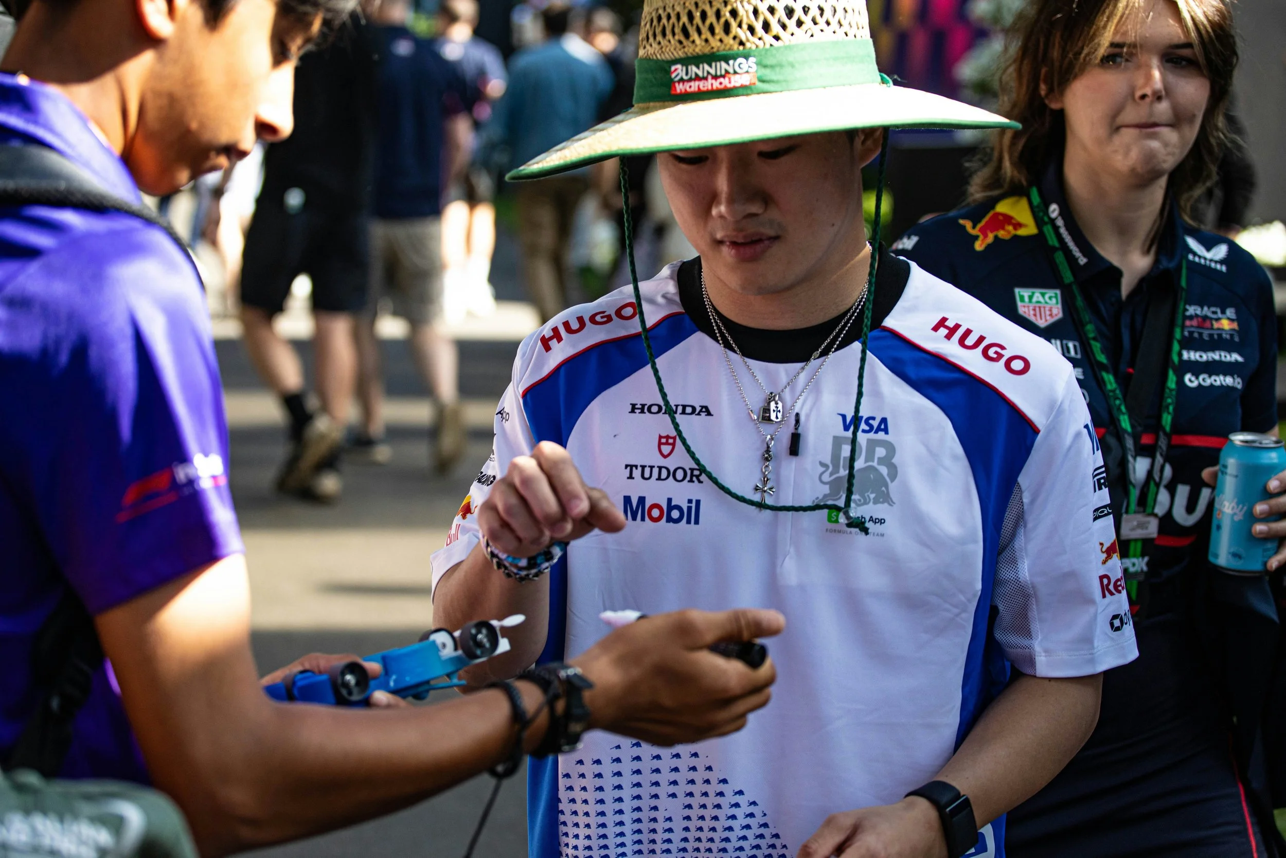 Yuki Tsunoda interacting with fans as an F1 content creator captures a busy paddock moment