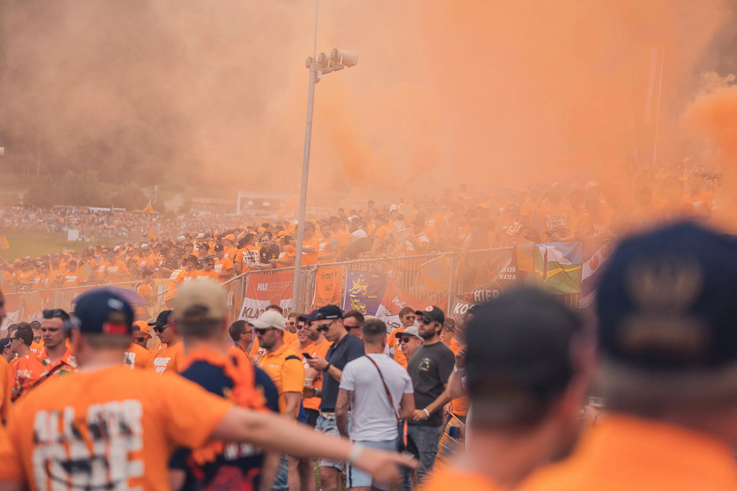 Dutch Formula 1 fans supporting Max Verstappen with orange smoke, showing high-energy fan engagement and crowd atmosphere