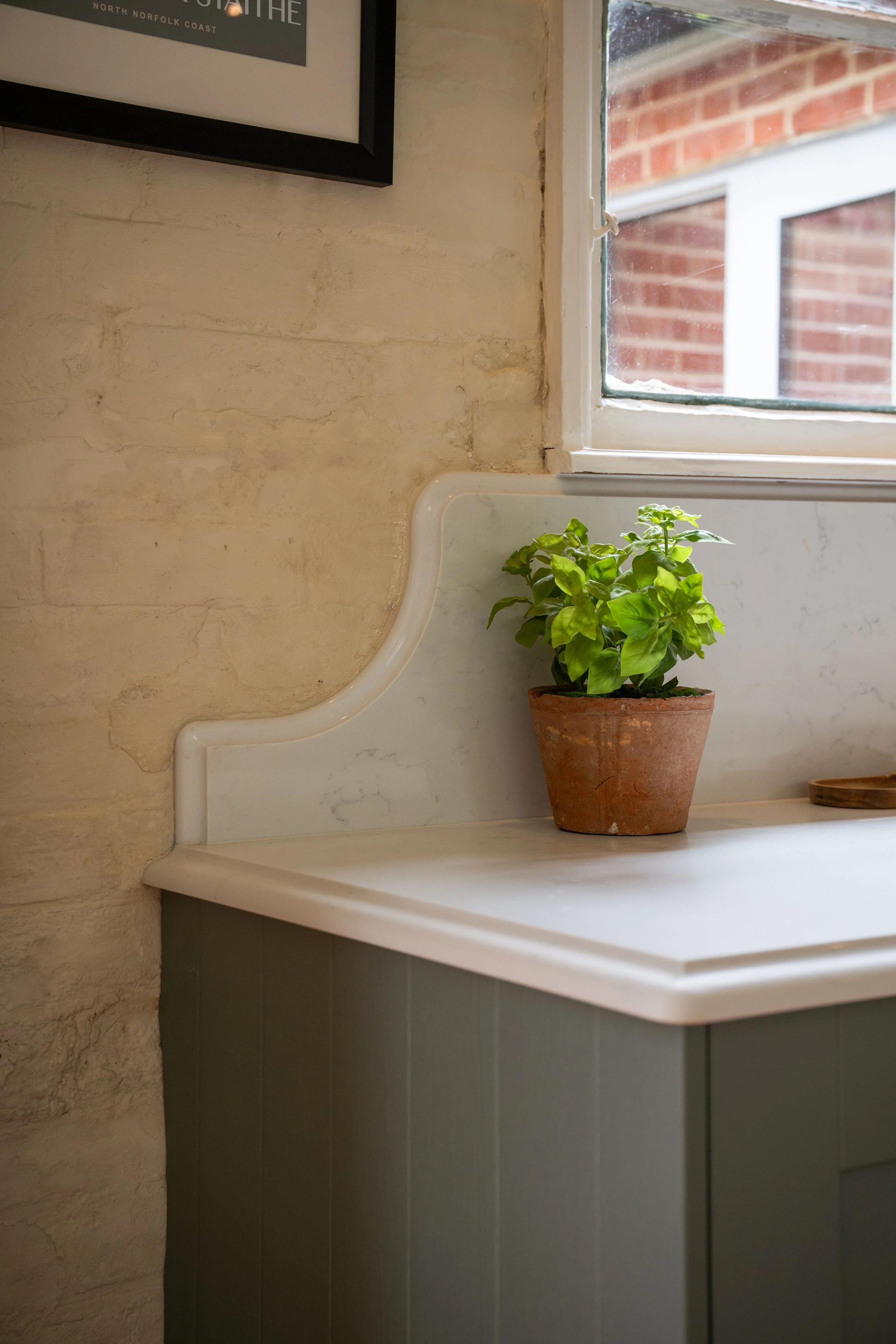 Bespoke Carrara Branco quartz worktop with a 20mm upstand shaped around the irregular wall beneath the original school window.