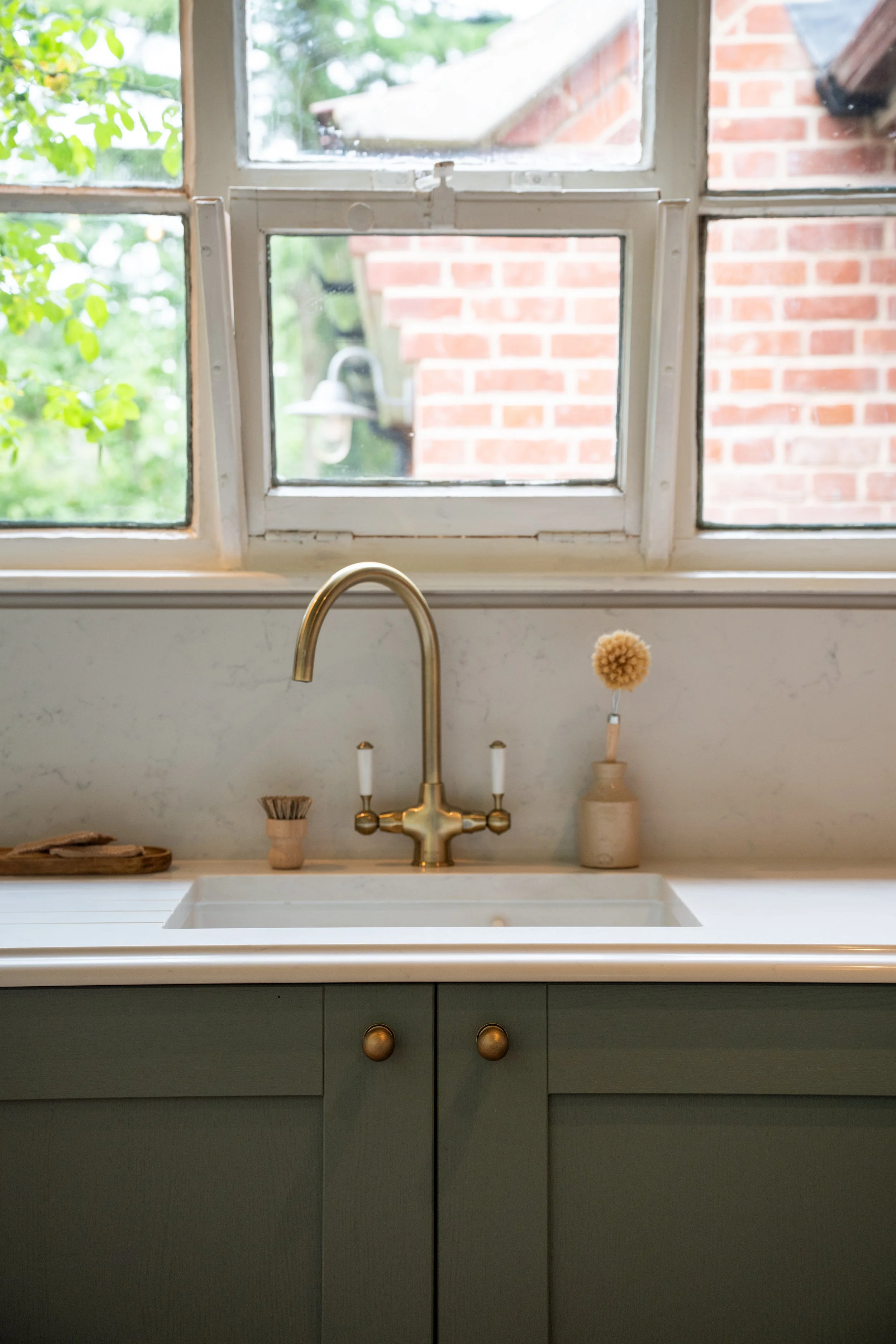 Caple Shaftesbury tap in warm brass with Rangemaster ceramic sink beneath the original school window.