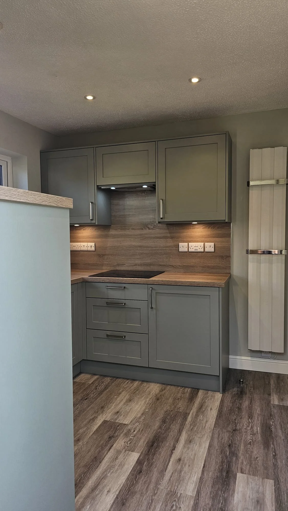 Modern gray kitchen with wood-look countertops and backsplash, gray cabinets, and a wood-paneled wall heater.