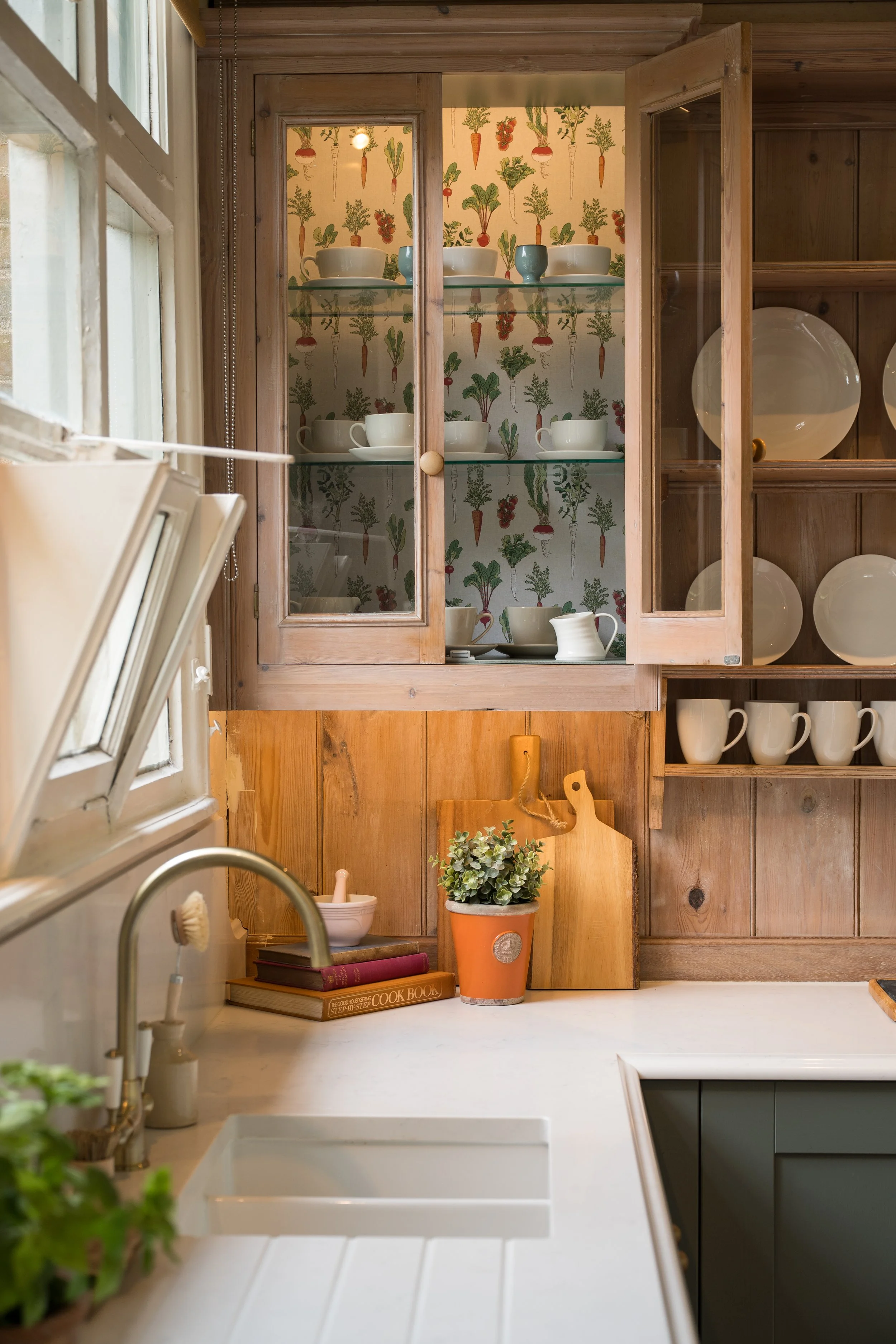 Updated glazed cabinet beside an original school window, with fabric-backed interior, glass shelving and integrated lighting.