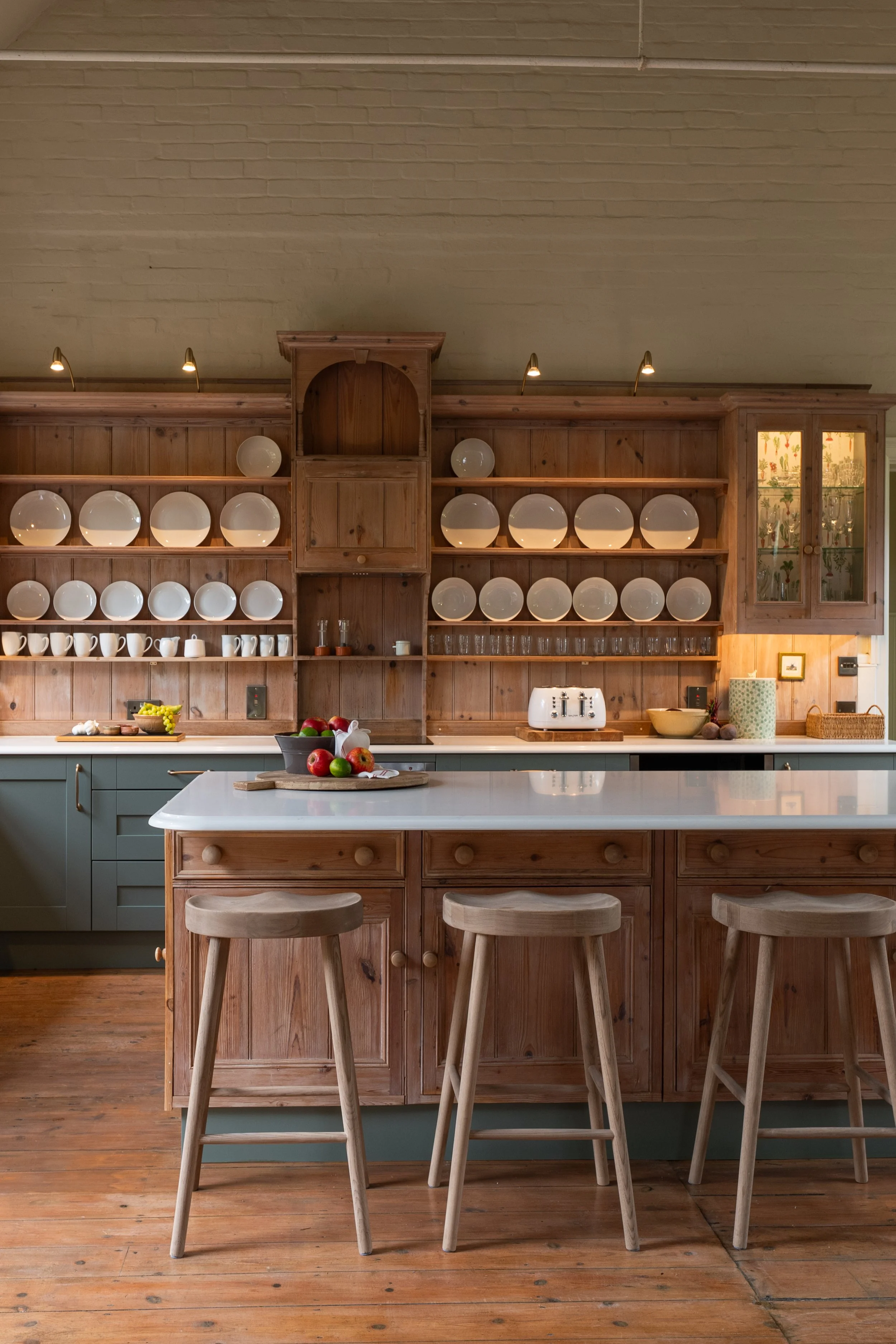 Bespoke kitchen in the former Great Snoring village school, combining a retained timber plate rack with a central island made using reused cabinetry.