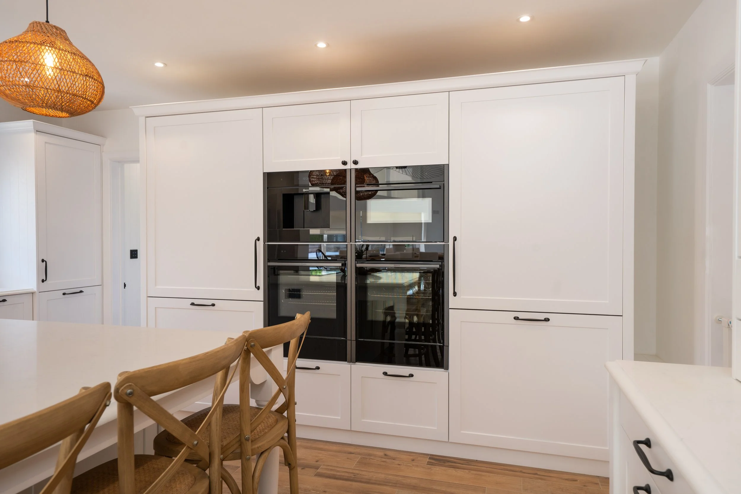 Painted Shaker cabinetry with integrated ovens and concealed appliance storage