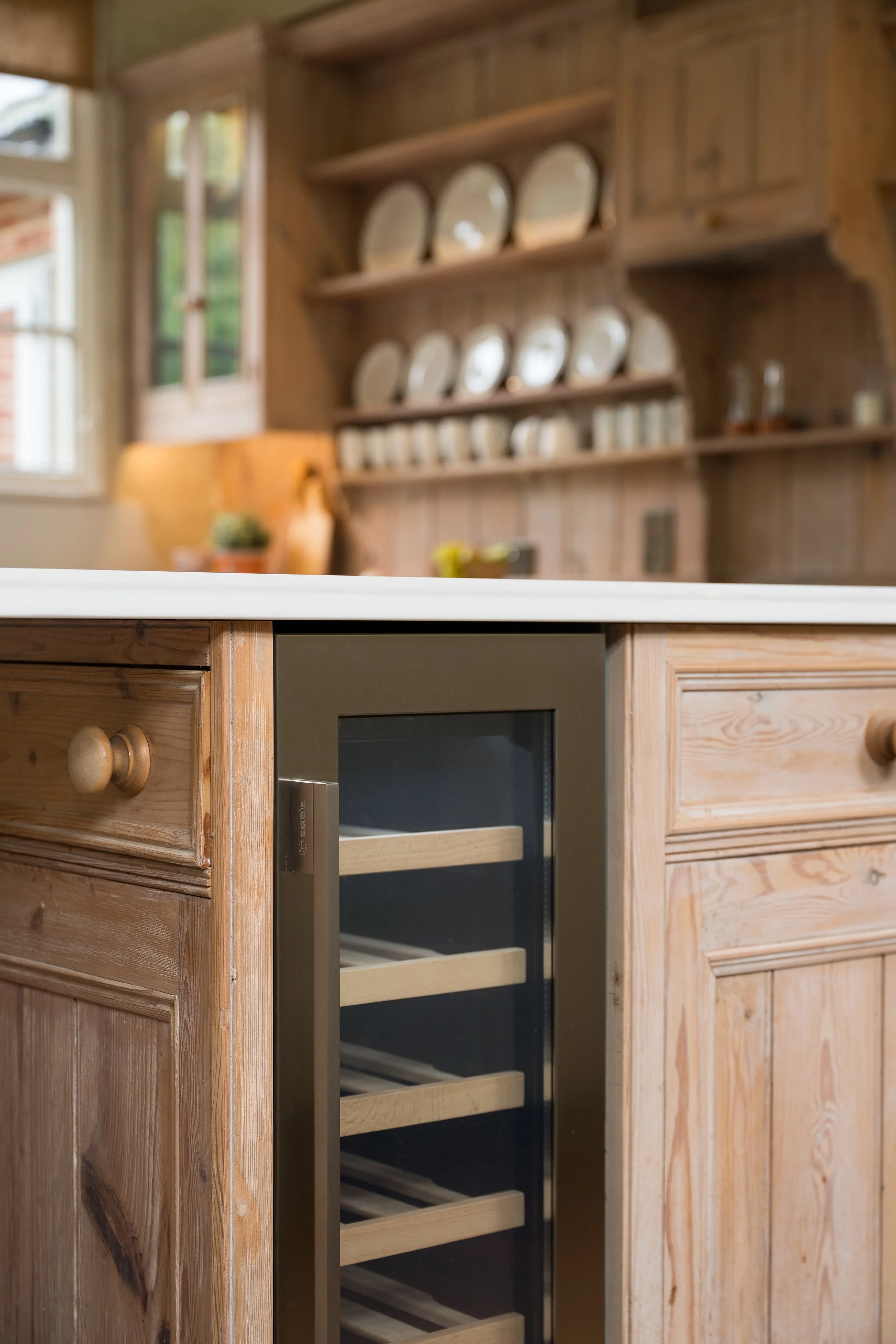 Caple wine chiller integrated into the kitchen island, surrounded by timber doors and panels reused from the previous kitchen.
