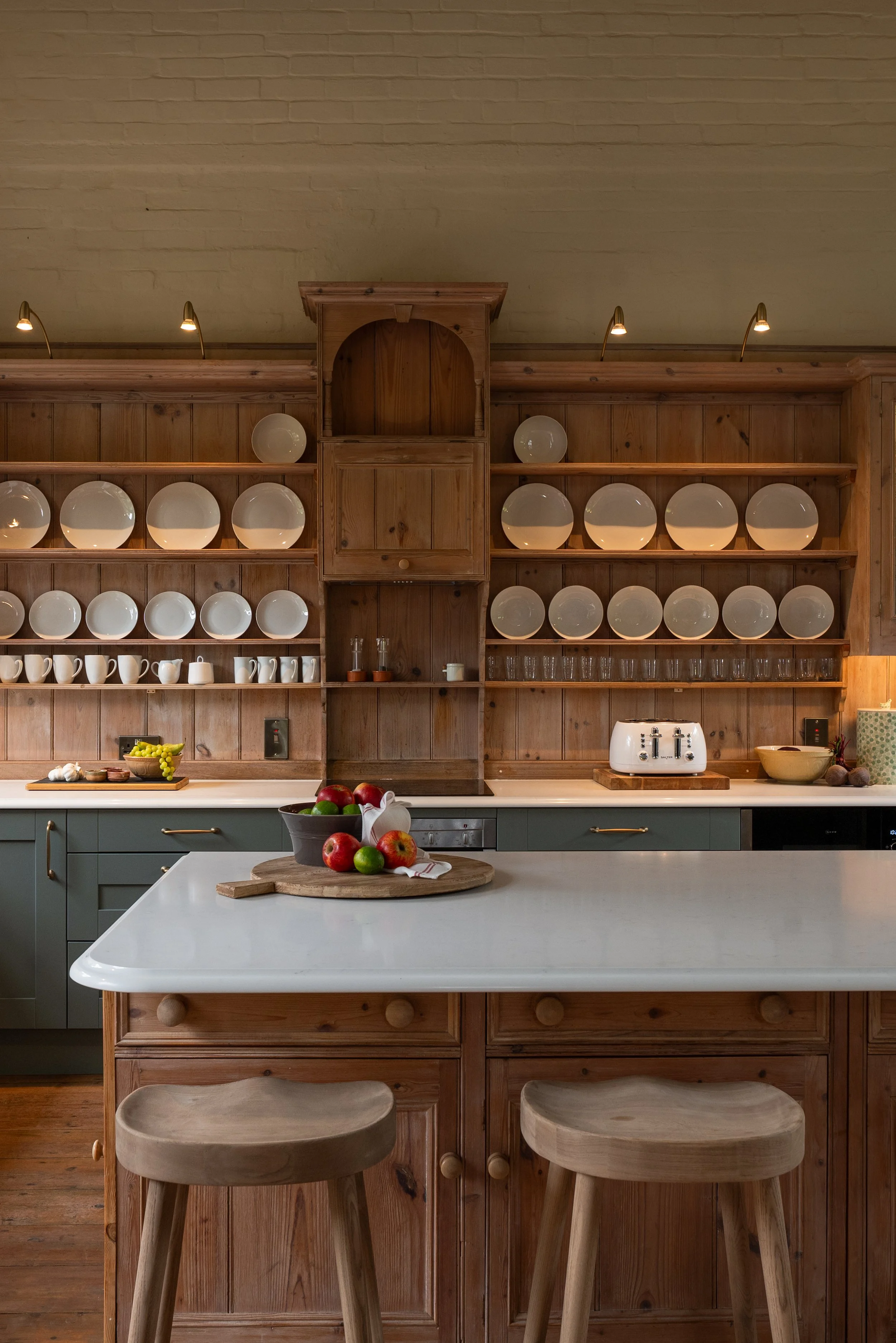 Retained timber plate rack with integrated lighting behind the reclaimed timber island in the Great Snoring School House kitchen.